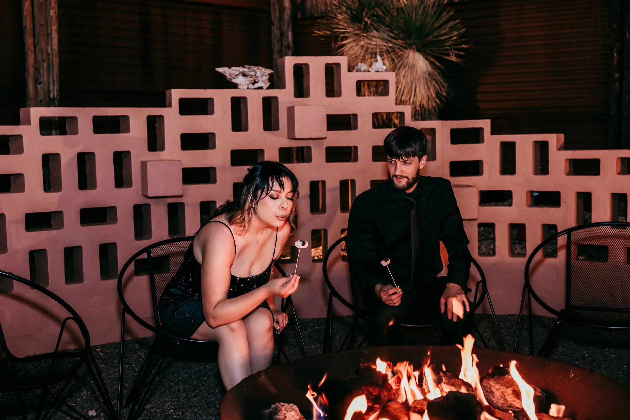 Newlywed couple roasting marshmallows around the fire pit during their evening reception at The Mystic in Santa Fe, New Mexico.