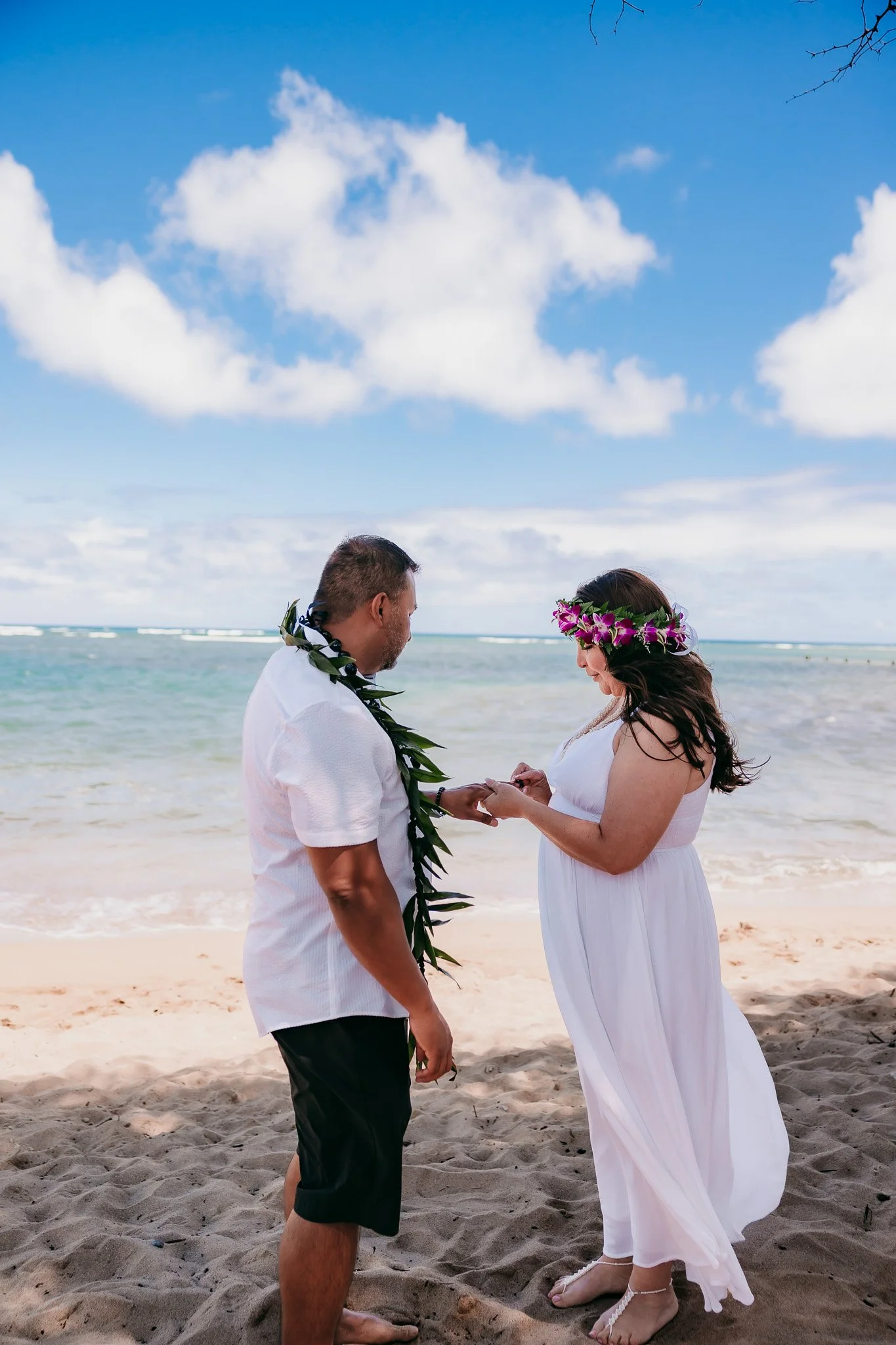 couple on the beach in Oahu Hawaii exchanging rings for a vow renewal destination wedding photography