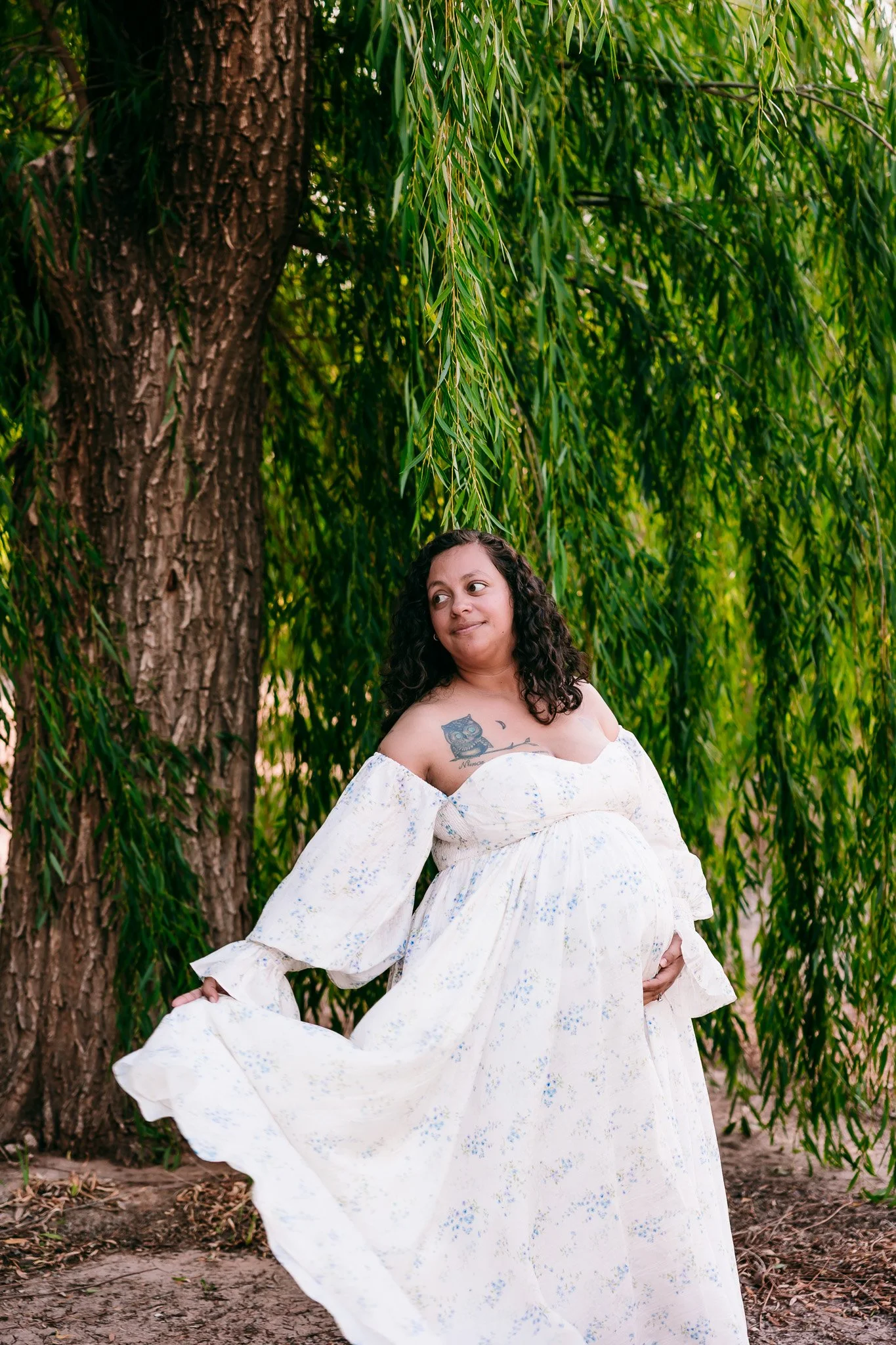 Expectant mother standing beneath willow trees during a natural maternity portrait session in Las Cruces, New Mexico.
