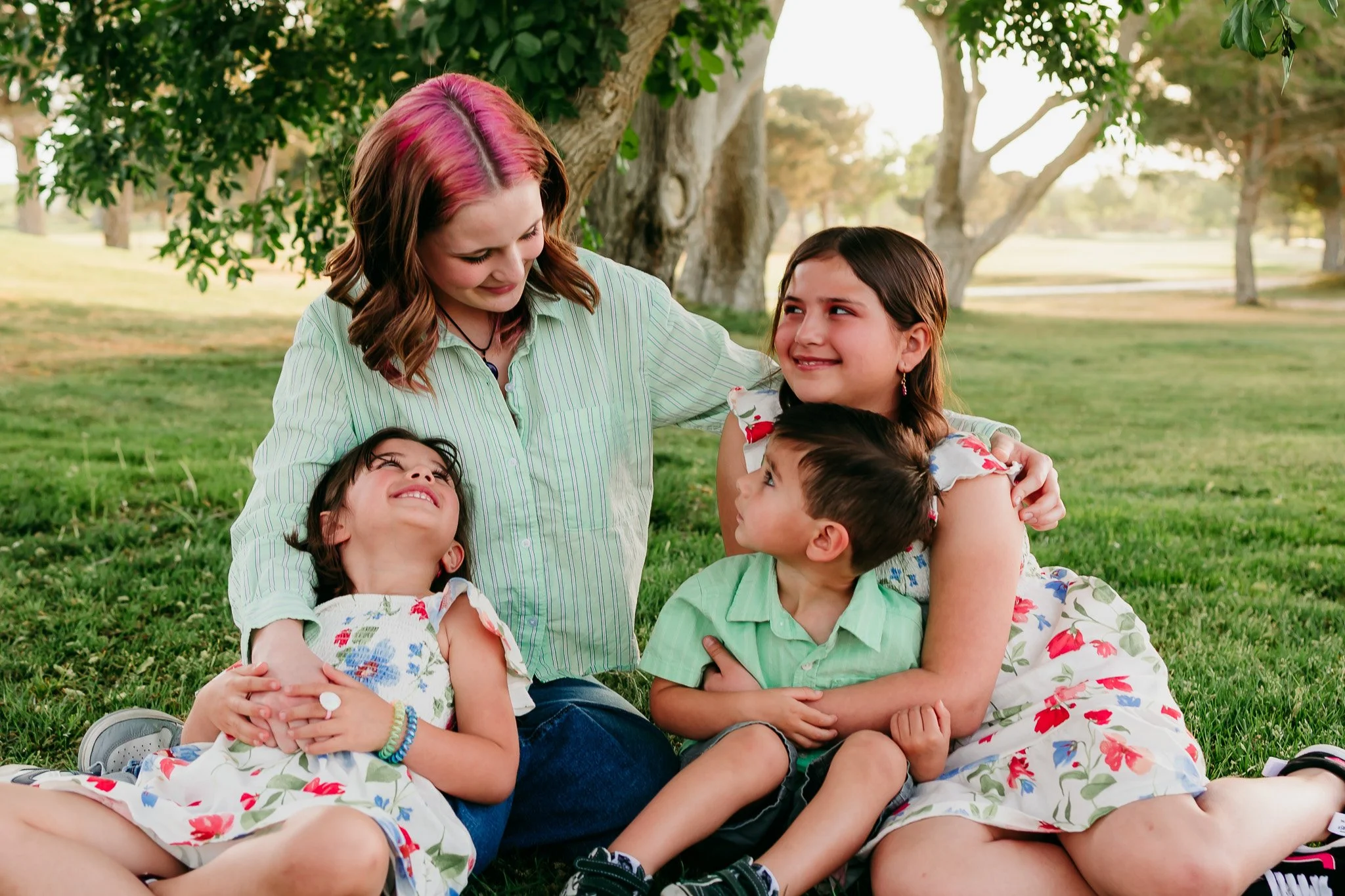 Siblings sitting together during a candid family photography session at NMSU Golf Course in Las Cruces, New Mexico.