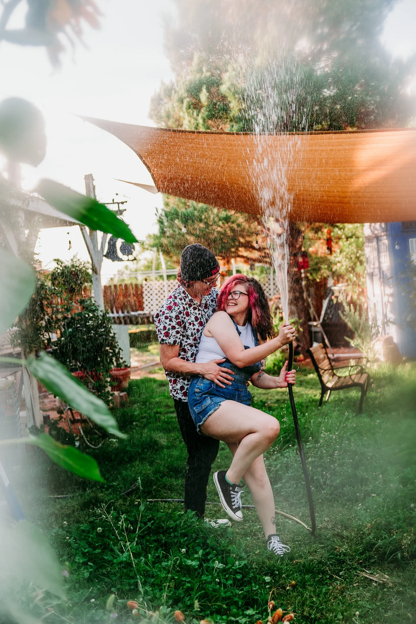 Couple laughing together during a playful backyard garden couples session at their home in Las Cruces, New Mexico.