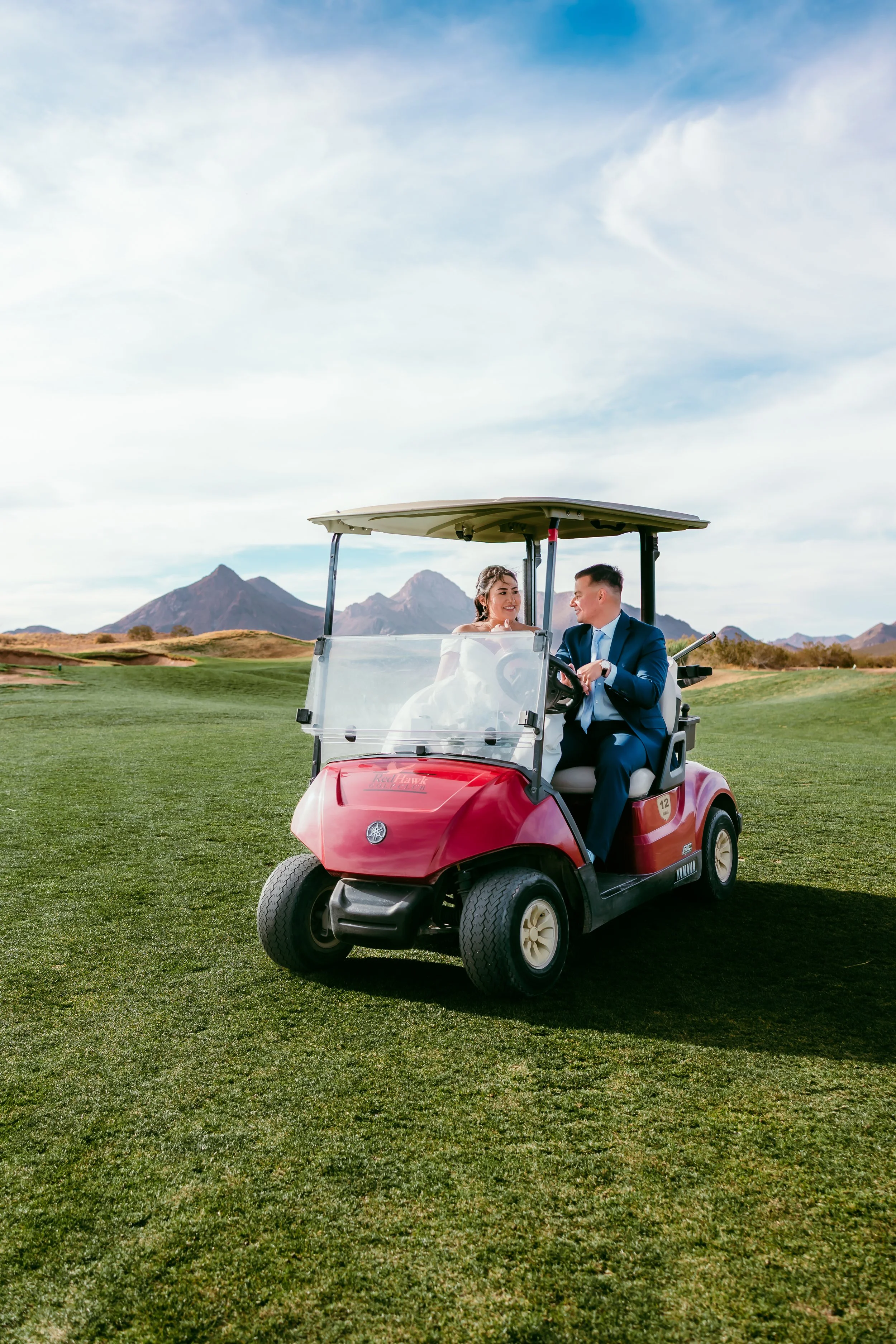 Bride and groom smiling together in a golf cart during wedding portraits at Red Hawk Golf Club in Las Cruces with the Organ Mountains in the background.