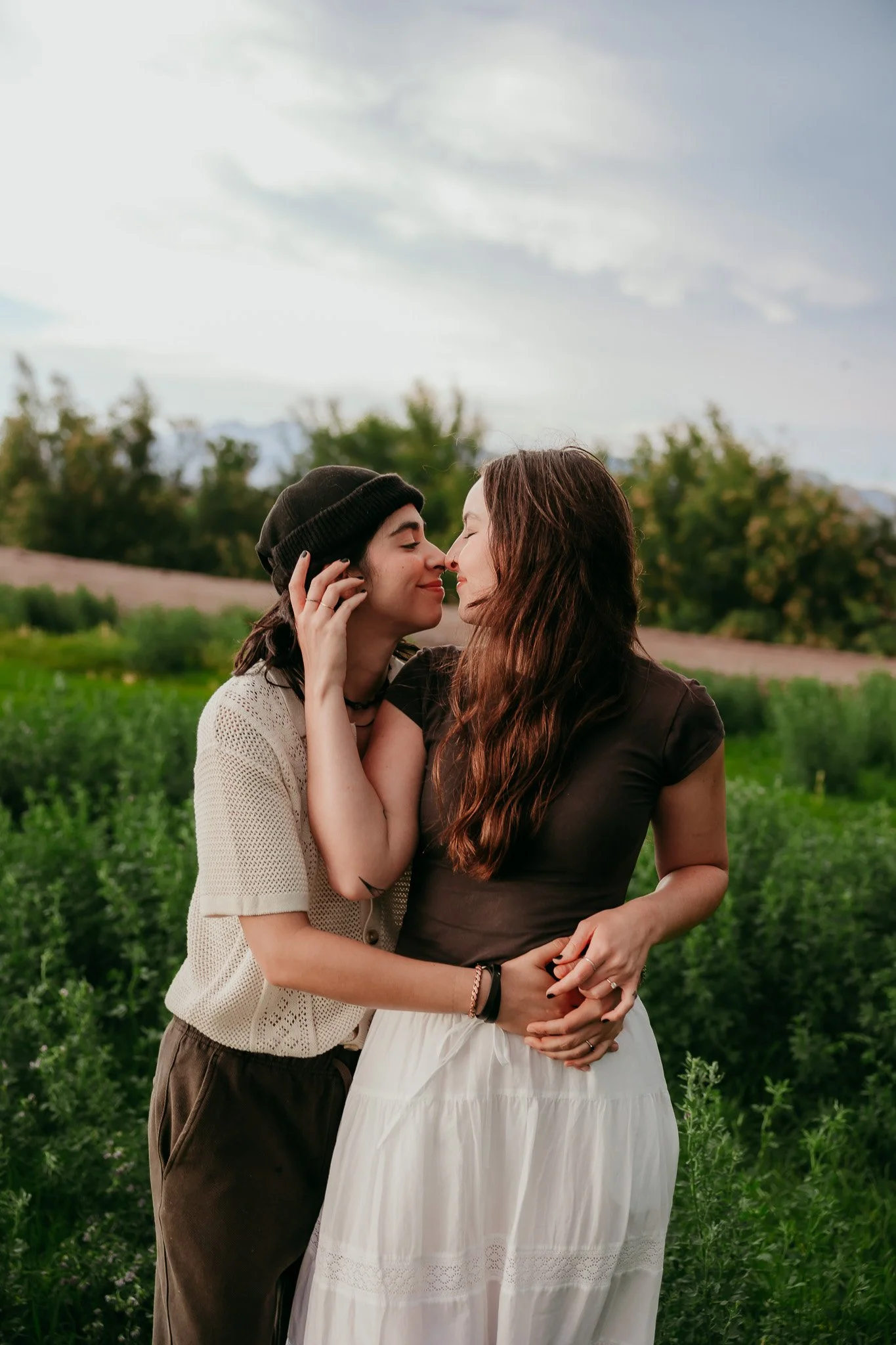 Partners holding hands and dancing through a green field during a romantic couples photography session in Mesilla, New Mexico. LGBT love. 