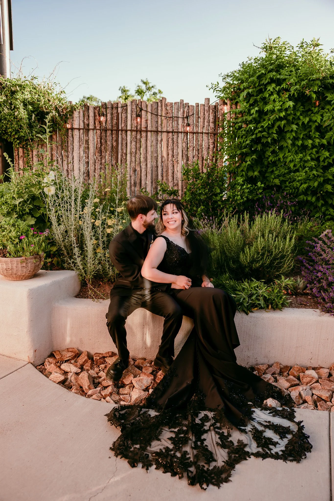 Newlywed couple in black wedding attire sitting together in the garden during their intimate wedding at The Mystic in Santa Fe, New Mexico.