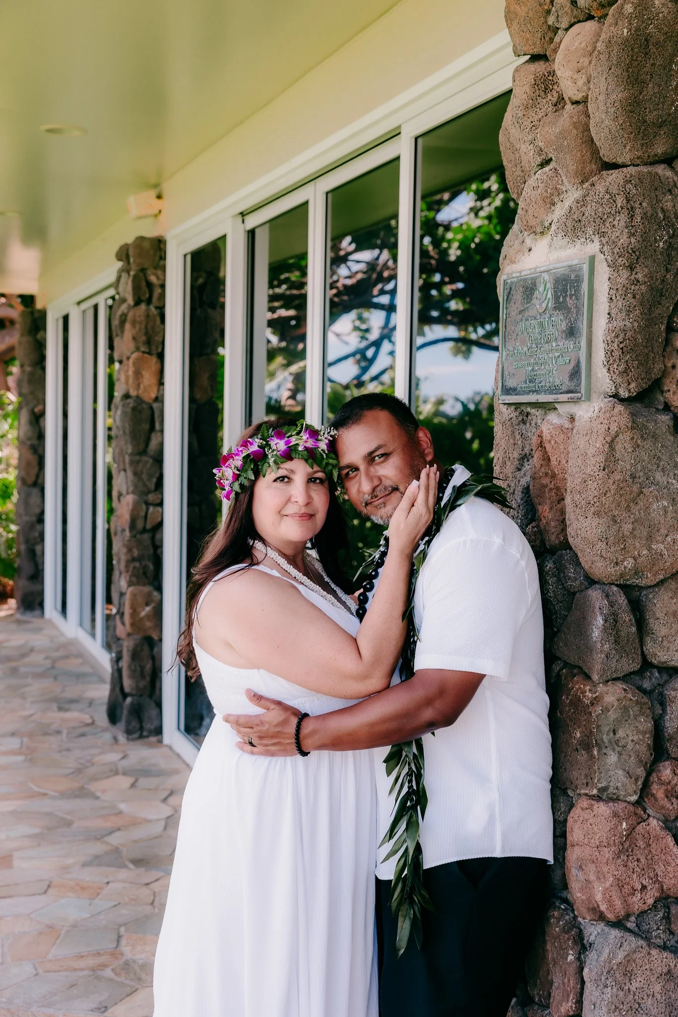 Newlyweds smiling at the camera on the beach during their destination wedding on Oahu, Hawaii.