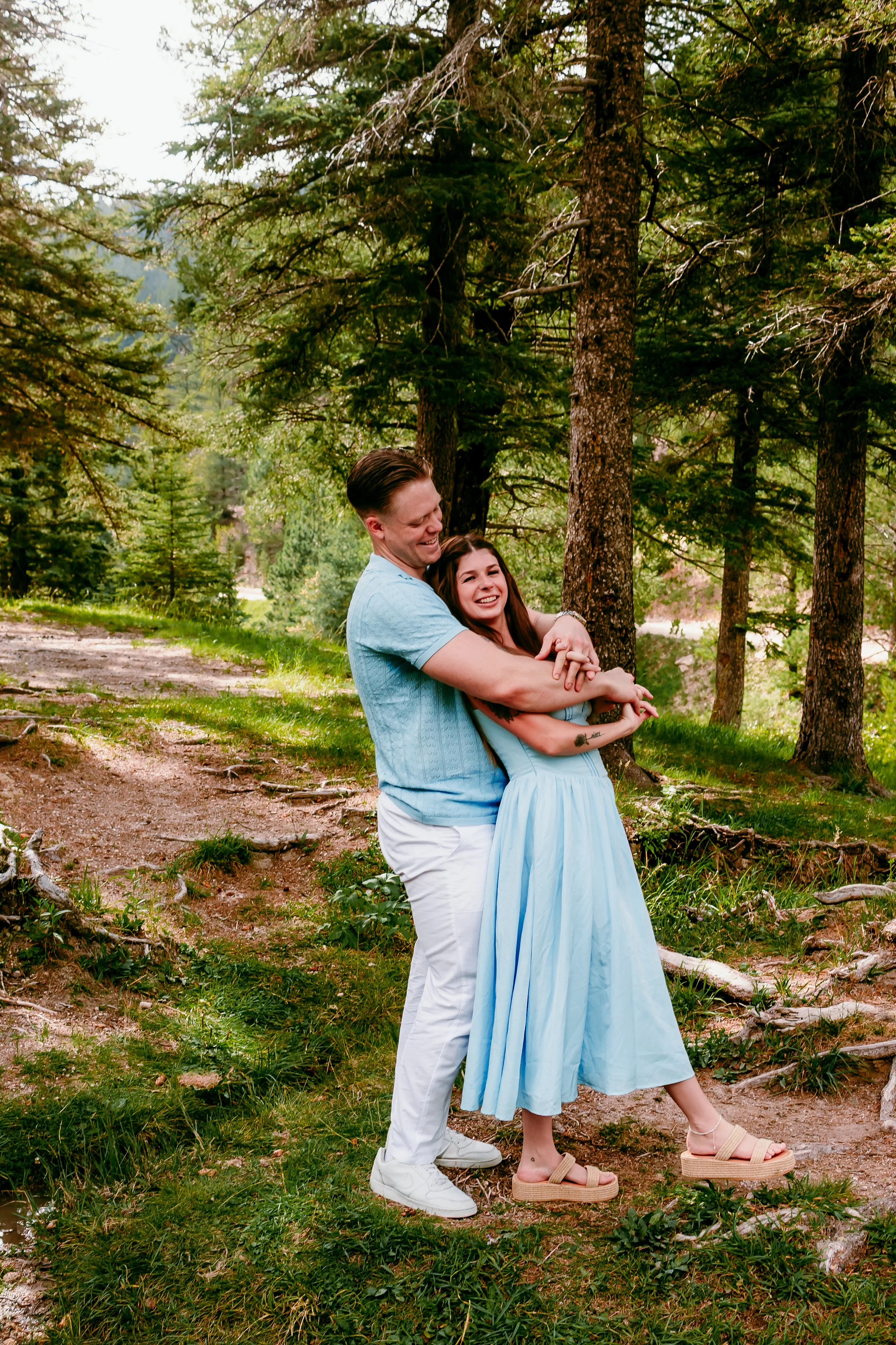 Couple laughing together while embracing in the mountain forest during their engagement session in Cloudcroft, New Mexico.