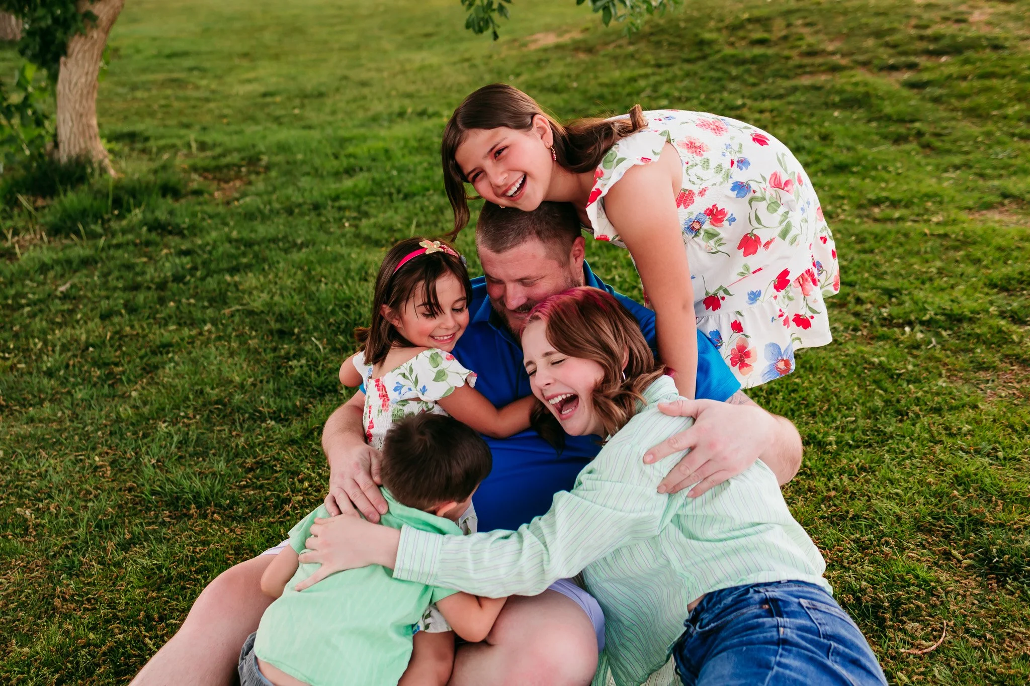 Family sharing laughs together on the grass during a relaxed outdoor family session at NMSU Golf Course in Las Cruces.
