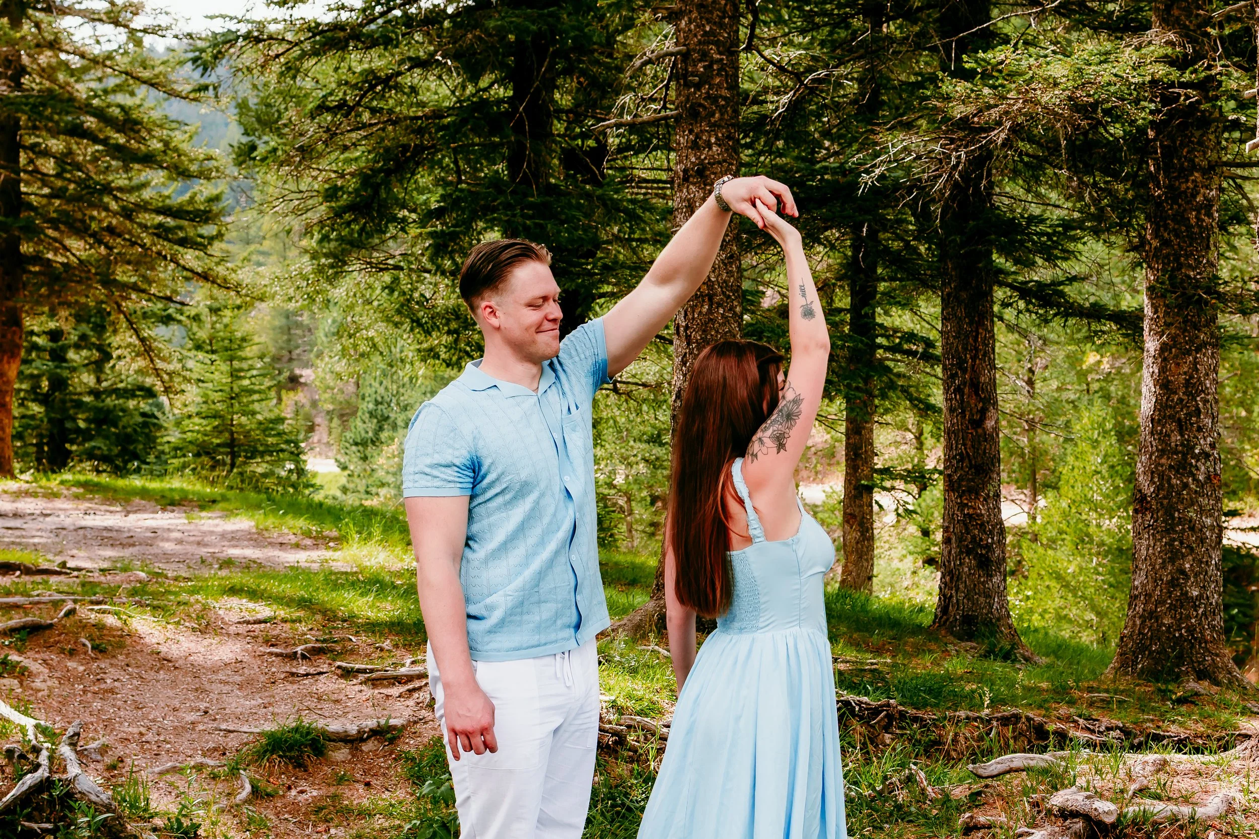 Couple twirling together beneath the tall pines during an adventurous engagement session in Cloudcroft, New Mexico.