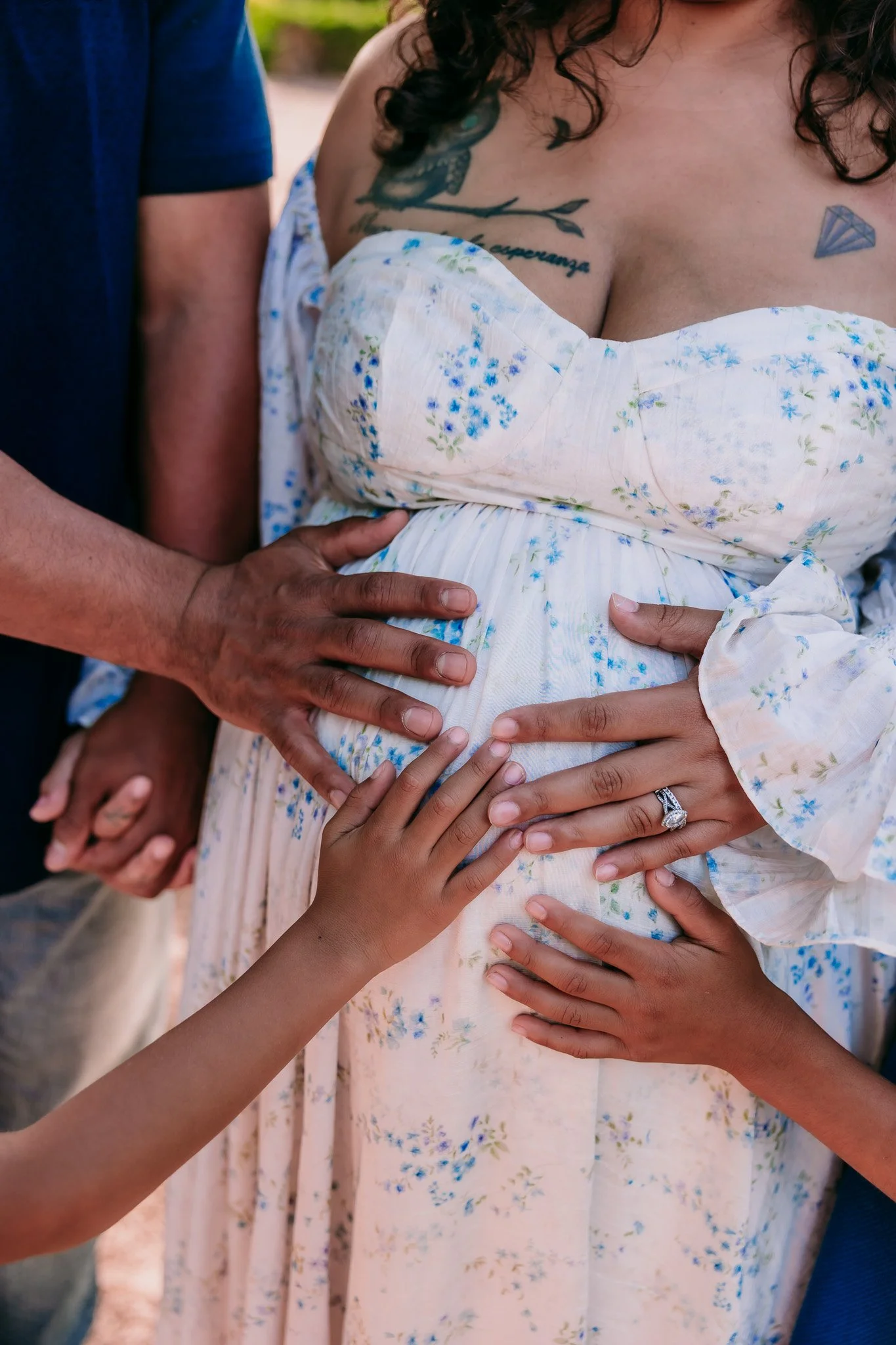 Parents and siblings placing their hands on a growing baby bump during a family maternity photography session in Las Cruces.