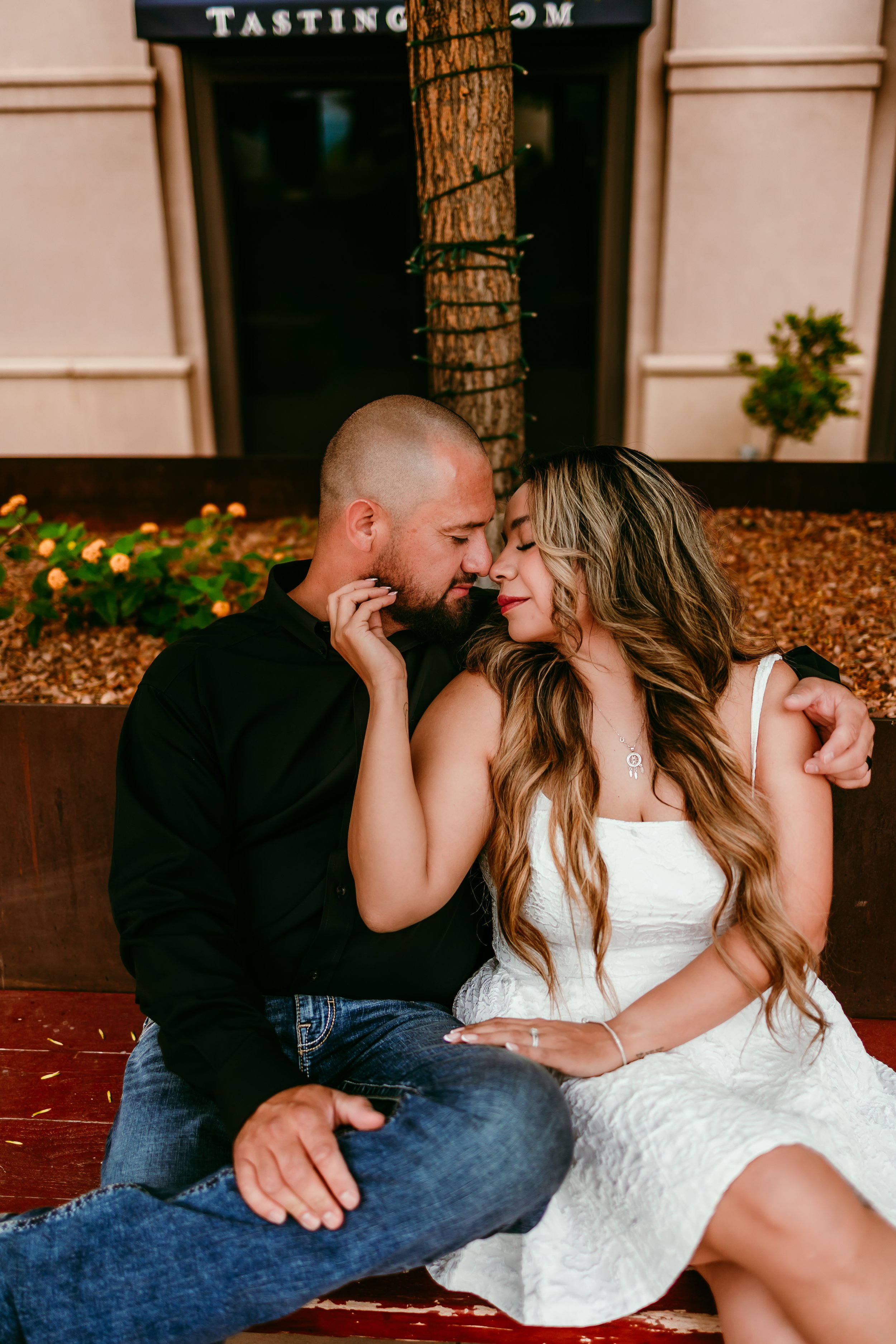 Couple cuddling on a downtown El Paso bench during a romantic engagement photography session in El Paso, Texas.