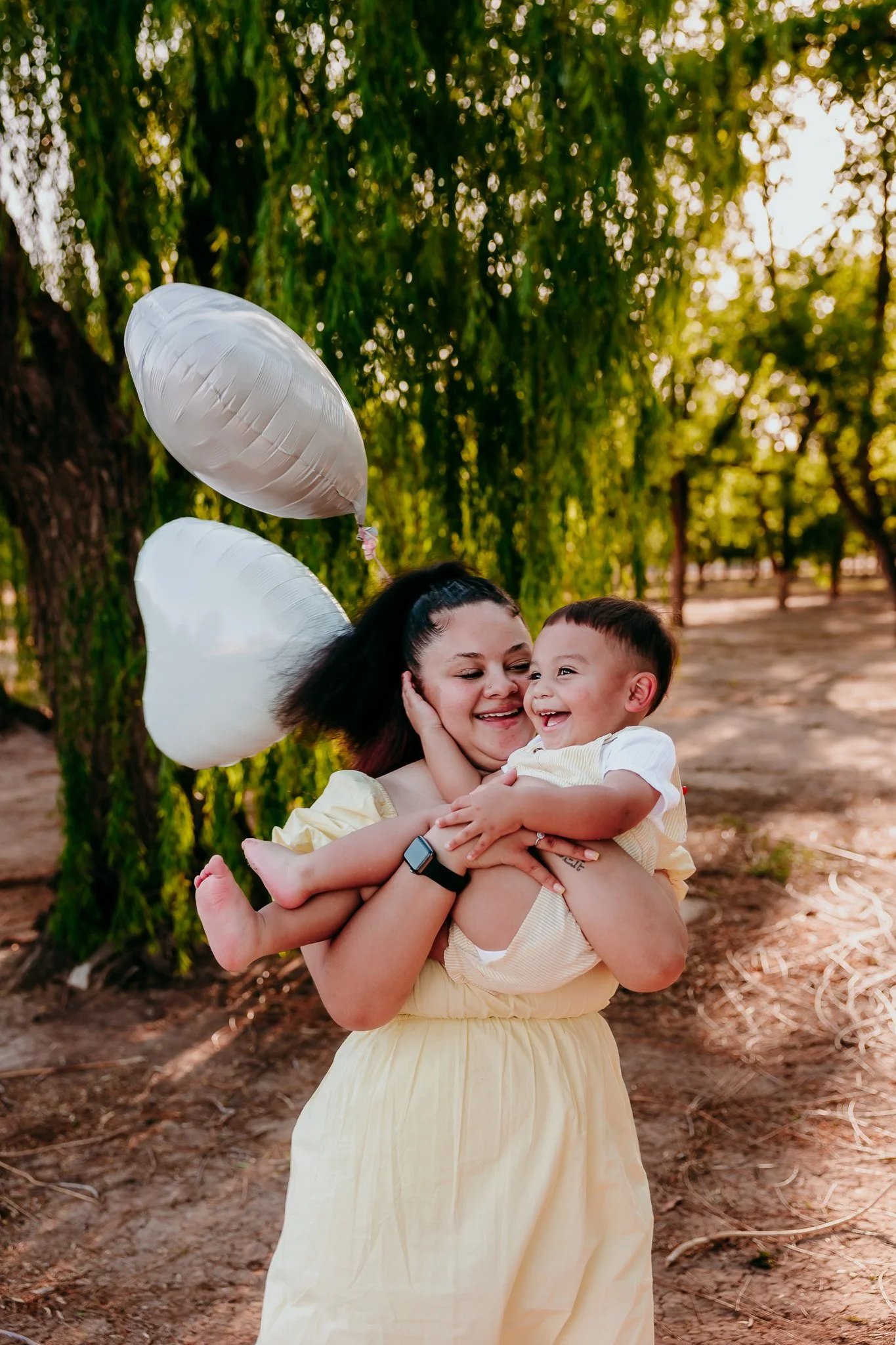 La Mesa family photographer capturing a mother hugging her toddler beneath willow trees during an outdoor family photography session in southern New Mexico.