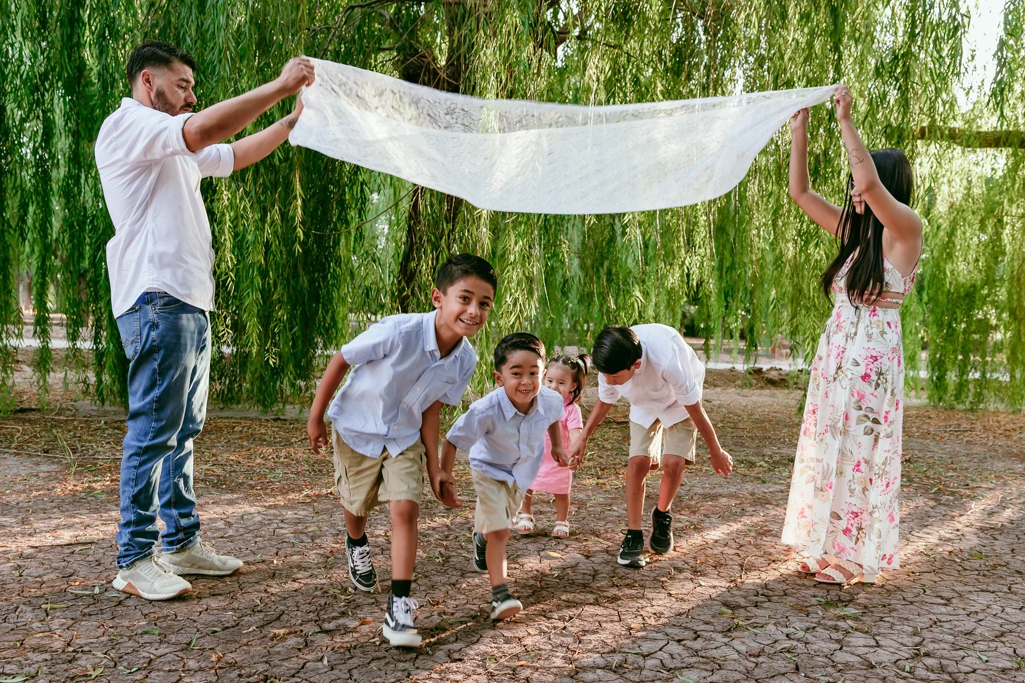 Playful family running beneath a flowing blanket during a lifestyle family photography session in Las Cruces.