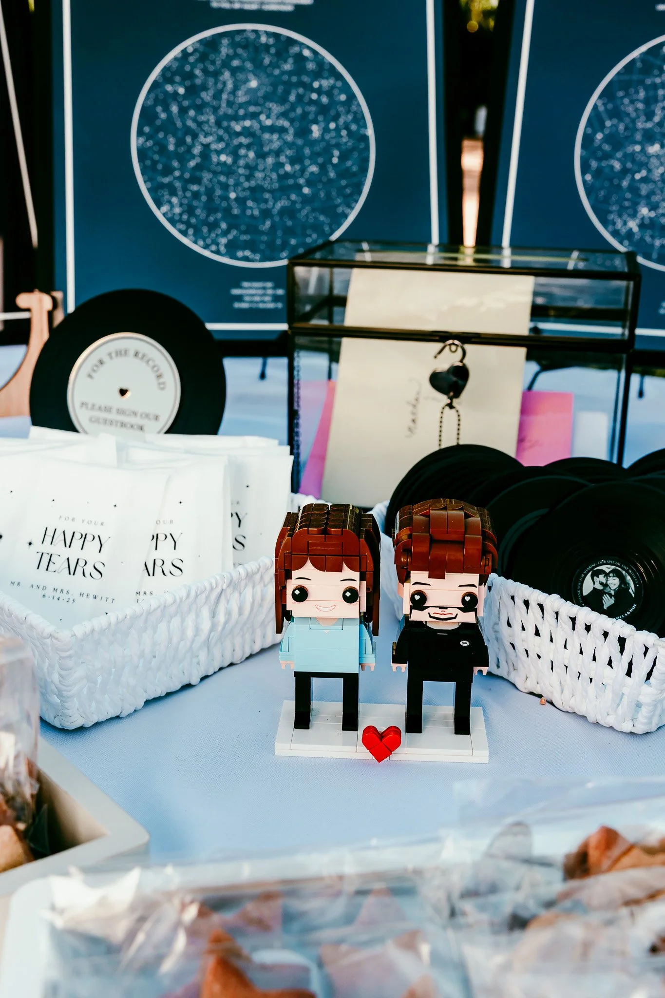Wedding welcome table with personalized guest favors, star map displays, happy tears packets, and custom LEGO cake topper at The Mystic in Santa Fe.