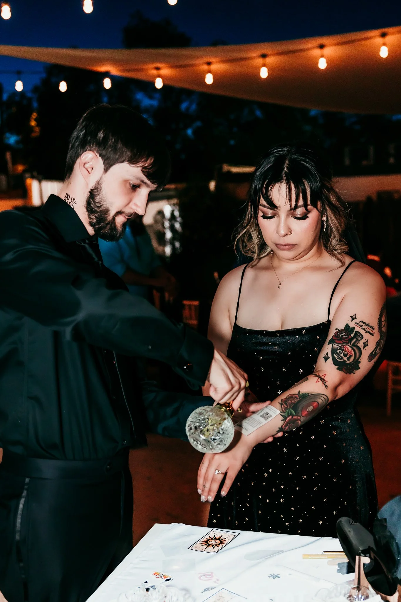Bride and groom applying temporary tattoos to each other at their tattoo bar during their intimate wedding reception at The Mystic in Santa Fe, New Mexico.