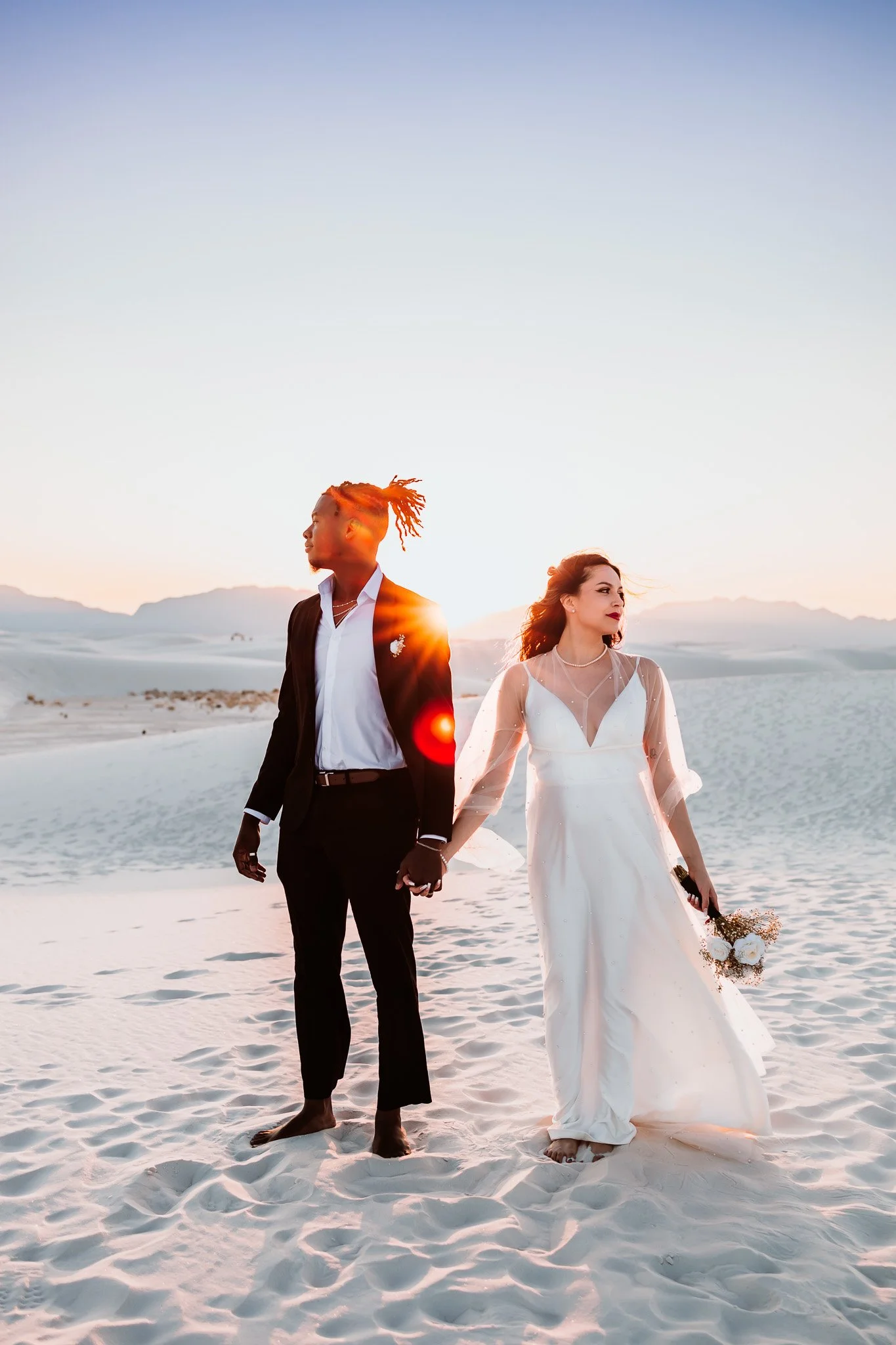 Bride and groom holding hands at sunset among the white gypsum dunes during their White Sands National Park elopement in New Mexico.