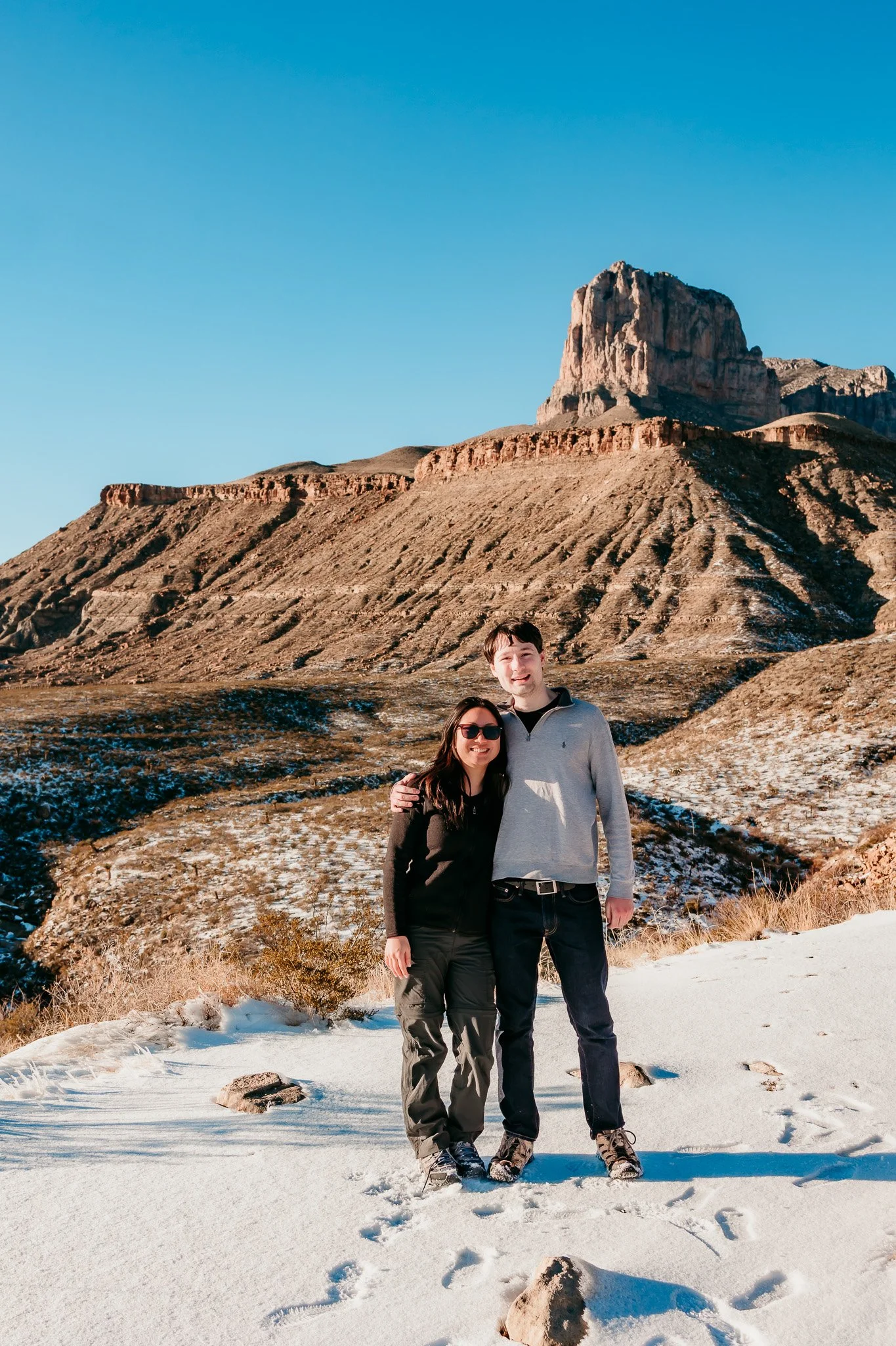 Couple standing together after a surprise proposal with the Guadalupe Mountains near Carlsbad, New Mexico in the background.