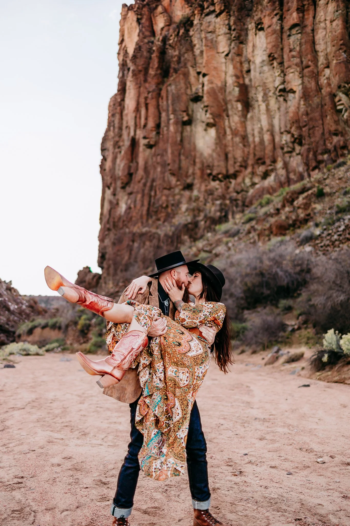 Couple sharing a playful dip pose beneath the cliffs during a romantic couples session at Diablo Canyon near Santa Fe, New Mexico.