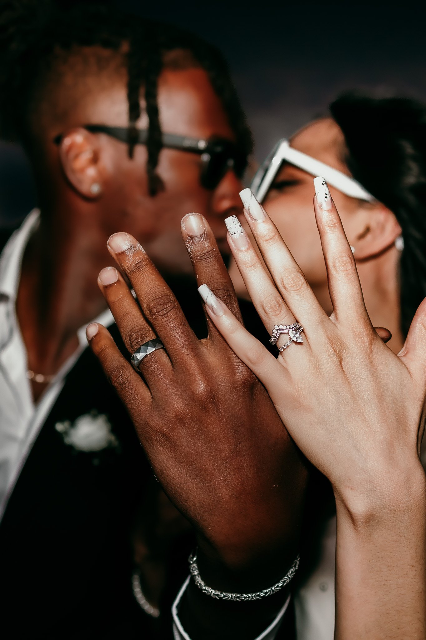 Bride and groom holding up their wedding rings while sharing a kiss after their White Sands National Park elopement.
