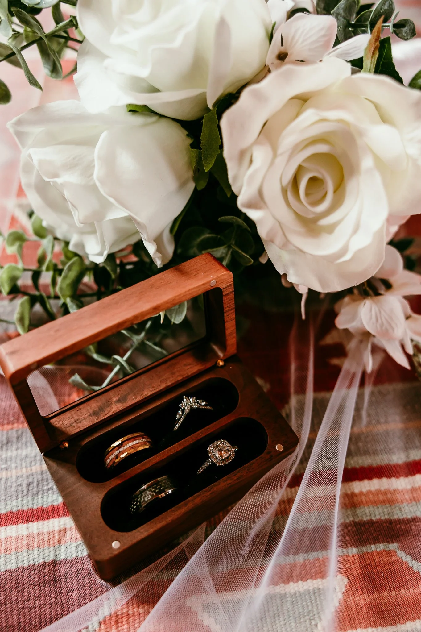 Wedding rings displayed in a wooden ring box beside a bridal bouquet during an intimate elopement at Abiquiu Lake in New Mexico.