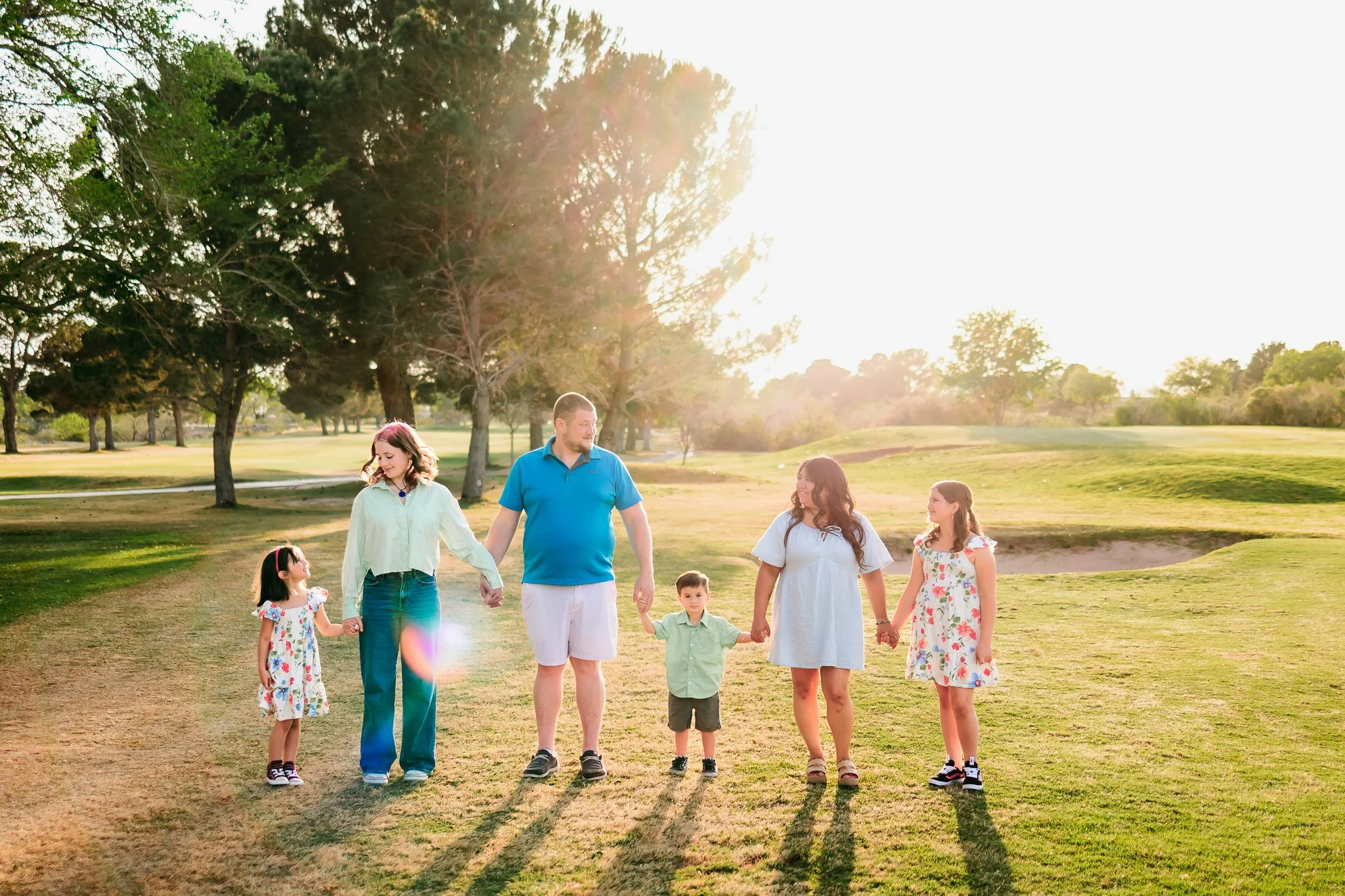 Family walking together at sunset during an outdoor family photography session at NMSU Golf Course in Las Cruces.