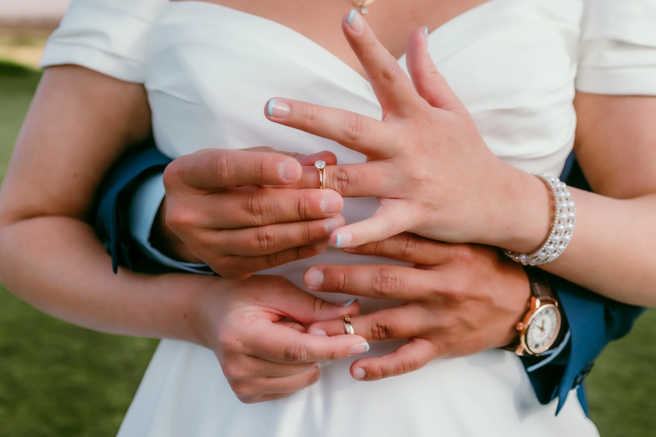 Bride and groom showing their wedding rings while embracing during portraits at Red Hawk Golf Club in Las Cruces, New Mexico.