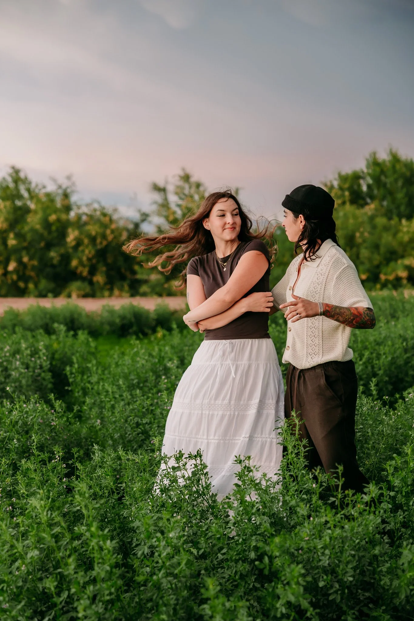 Couple smiling together in a lush field during a romantic couples session in Mesilla, New Mexico.