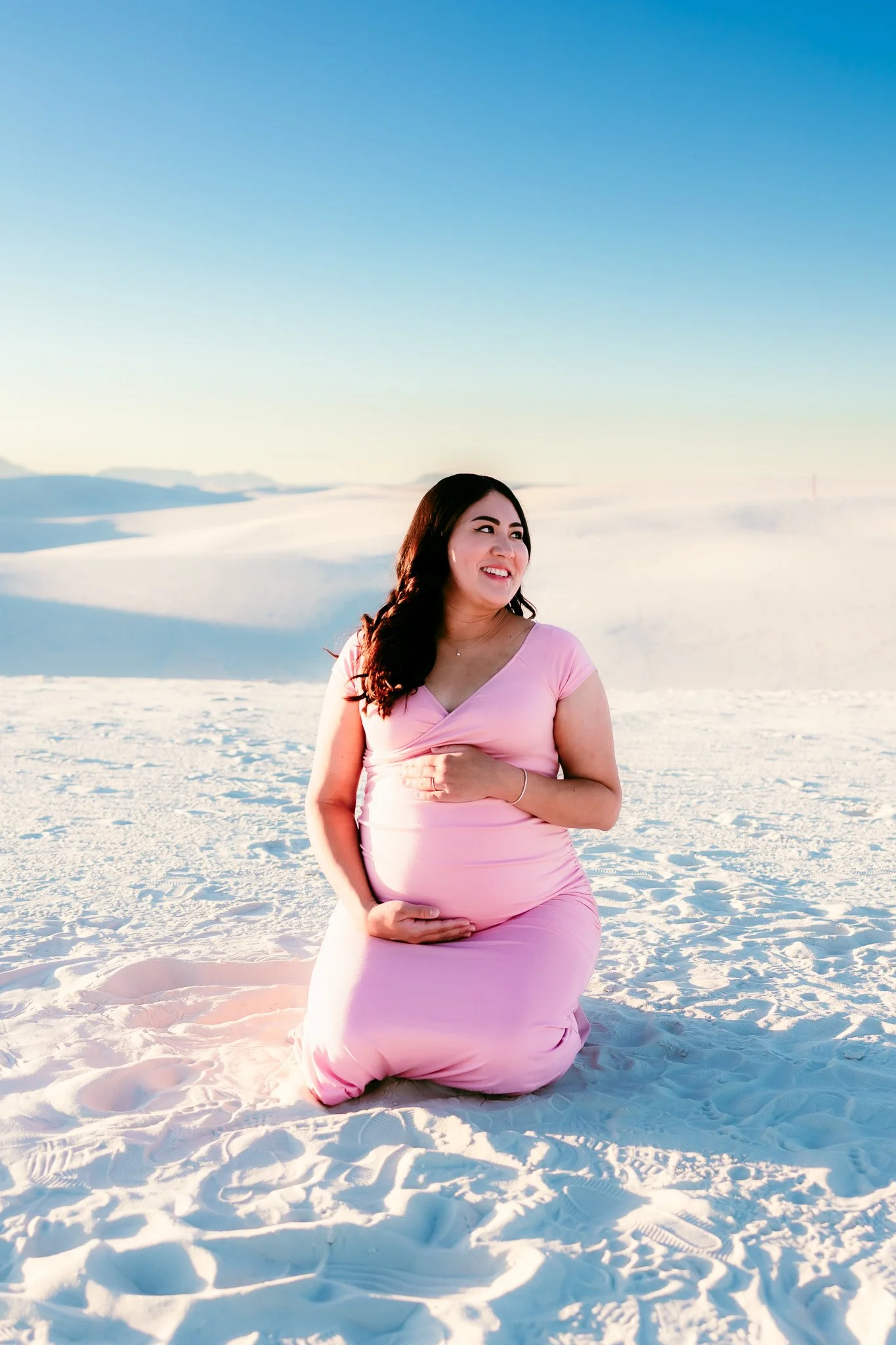 Expecting mother smiling during a golden hour maternity portrait at White Sands National Park captured by a White Sands maternity photographer.