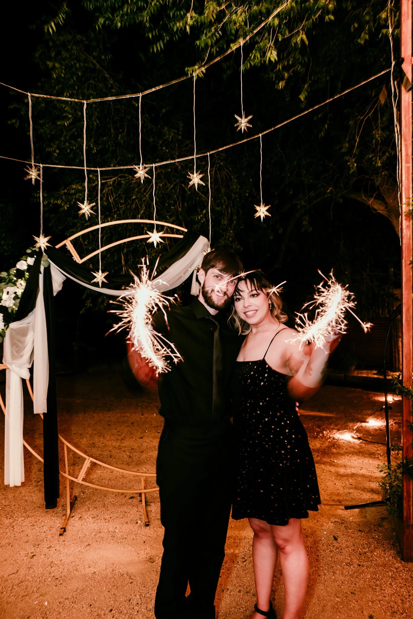 Newlywed couple celebrating with sparklers beneath their ceremony arch after their intimate wedding reception at The Mystic in Santa Fe, New Mexico.