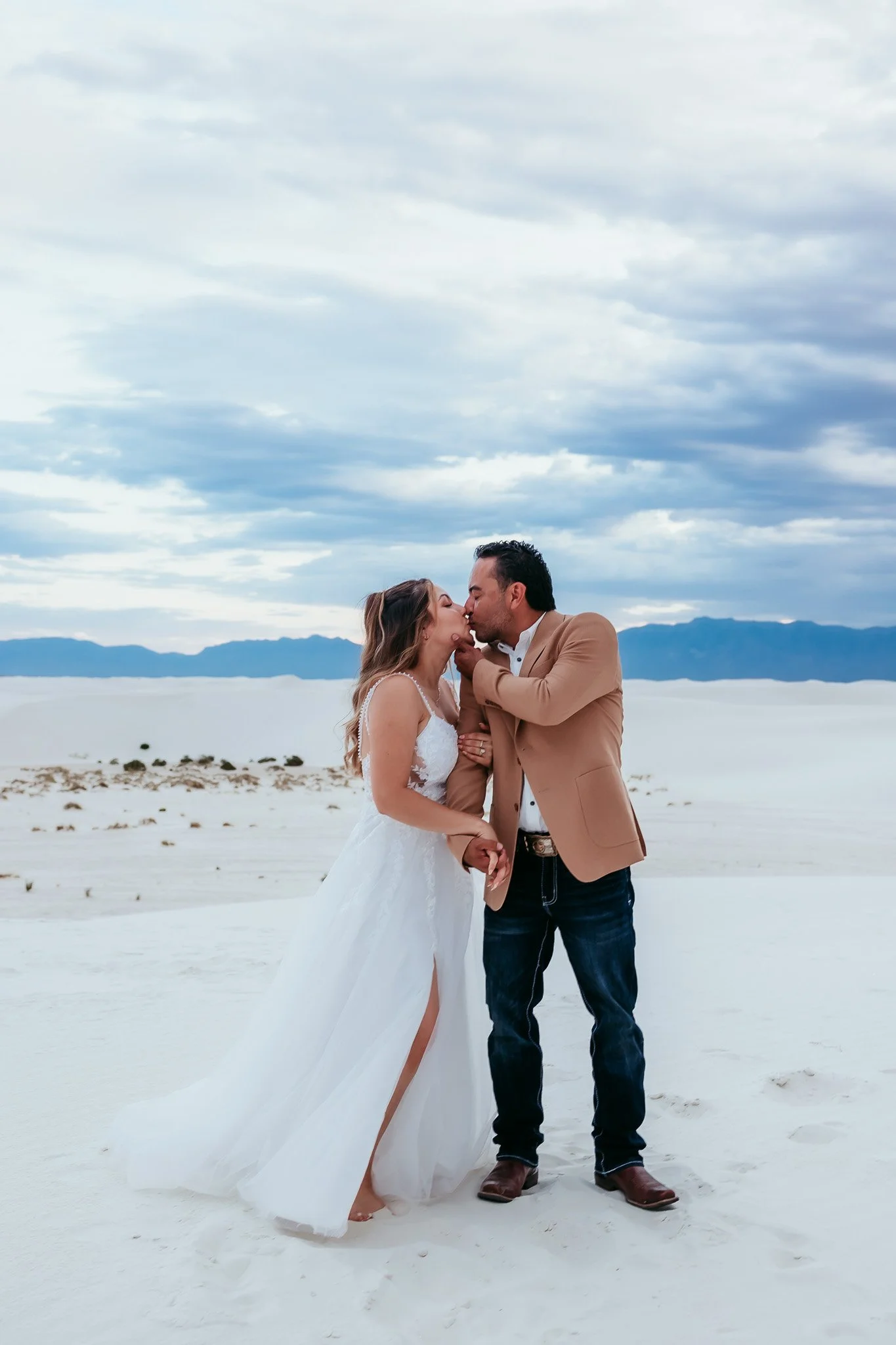 Newlyweds sharing a kiss during their romantic elopement portrait session at White Sands National Park in New Mexico.