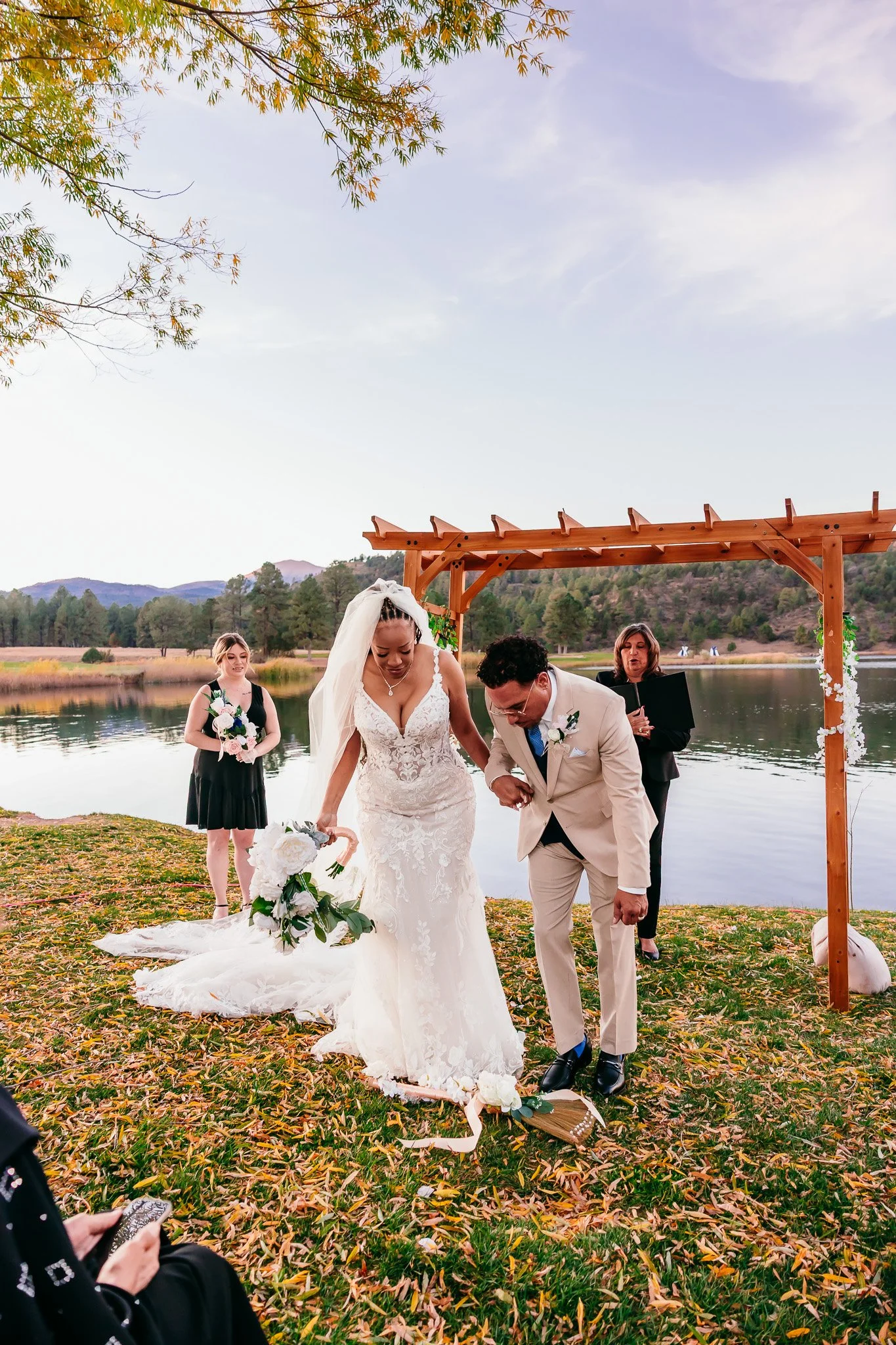 Bride and groom jumping over the broom after exchanging vows during their intimate wedding ceremony at Inn of the Mountain Gods in Ruidoso, New Mexico.