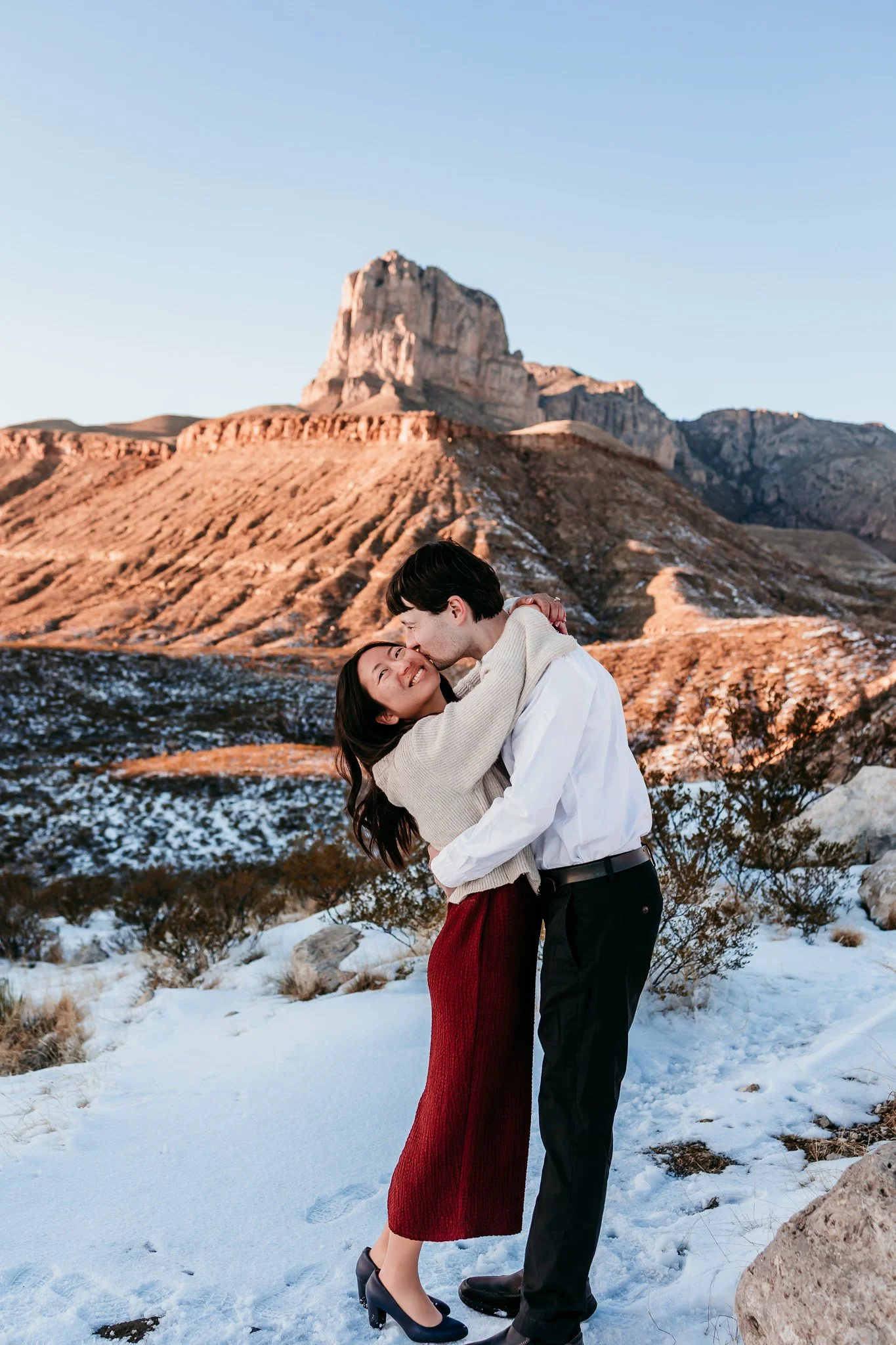 Couple walking hand in hand through the snowy desert after a surprise proposal at the Guadalupe Mountains near Carlsbad, New Mexico.