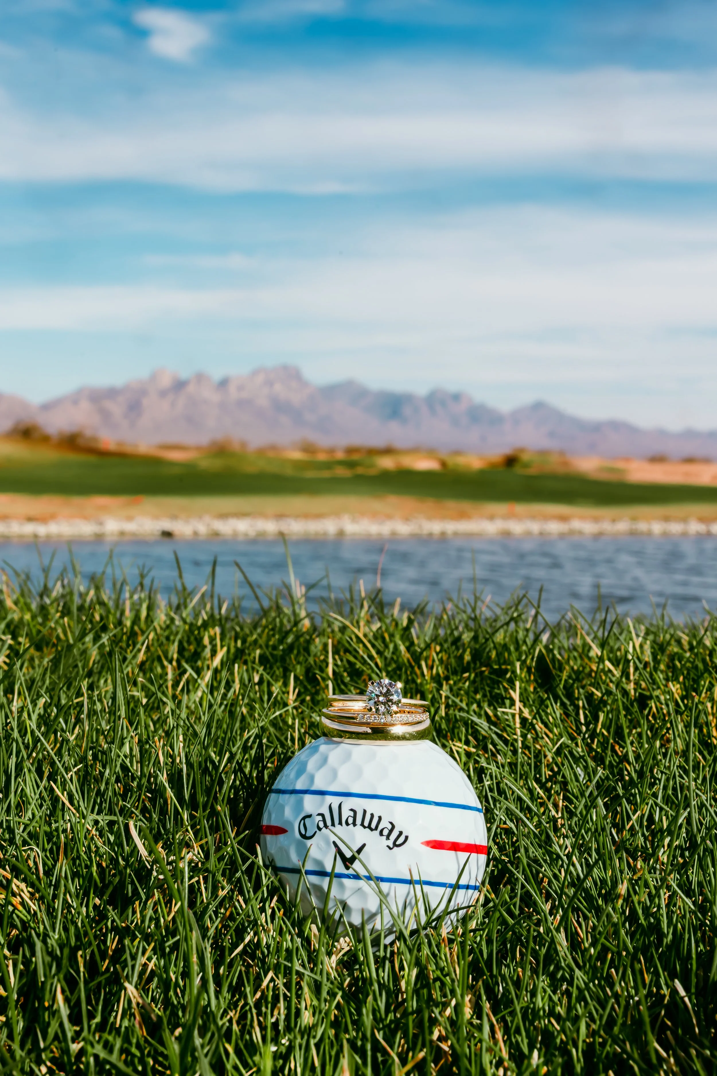 Wedding rings displayed on a golf ball overlooking the fairway at Red Hawk Golf Club in Las Cruces, New Mexico, with the Organ Mountains in the background.