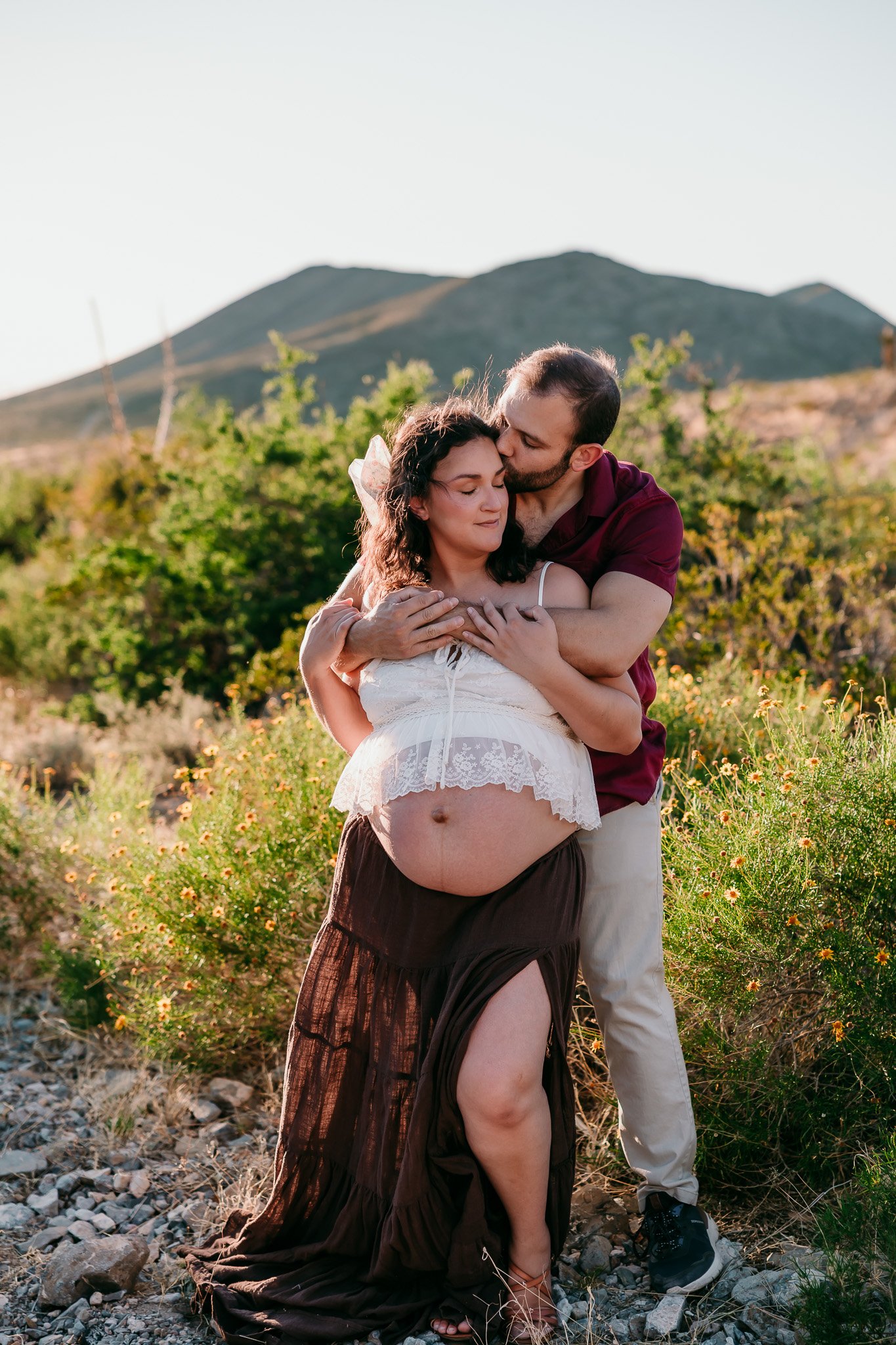 El Paso maternity photographer capturing expecting parents embracing during an outdoor maternity photography session in the El Paso mountains.
