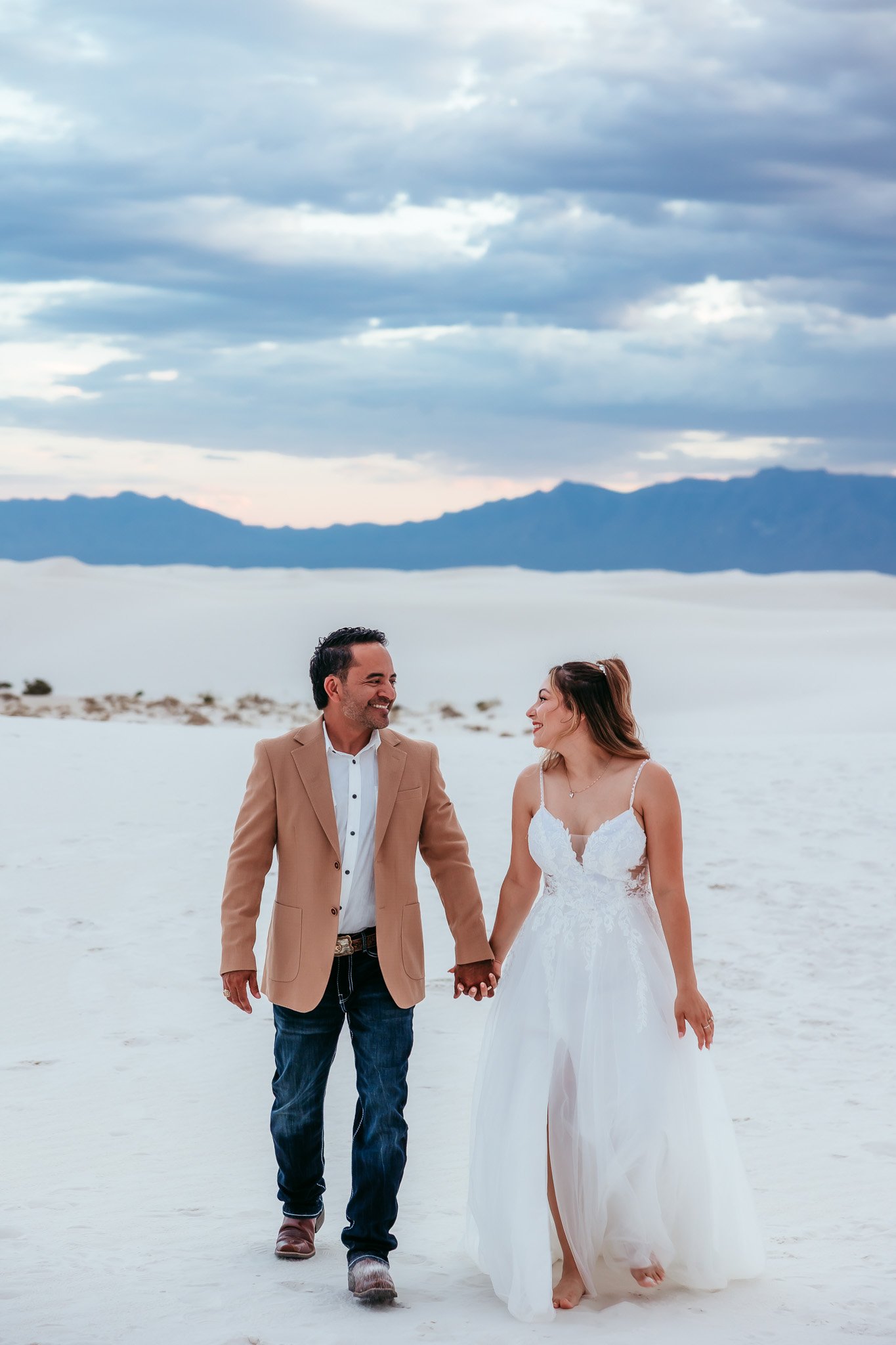 Newlyweds walking together while holding hands at White Sands National Park in New Mexico during their elopement.