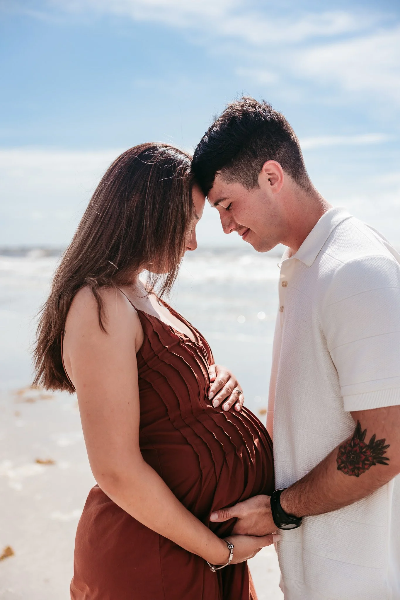 Expecting parents sharing an intimate moment while celebrating their pregnancy during a beach maternity session in Jacksonville, Florida.