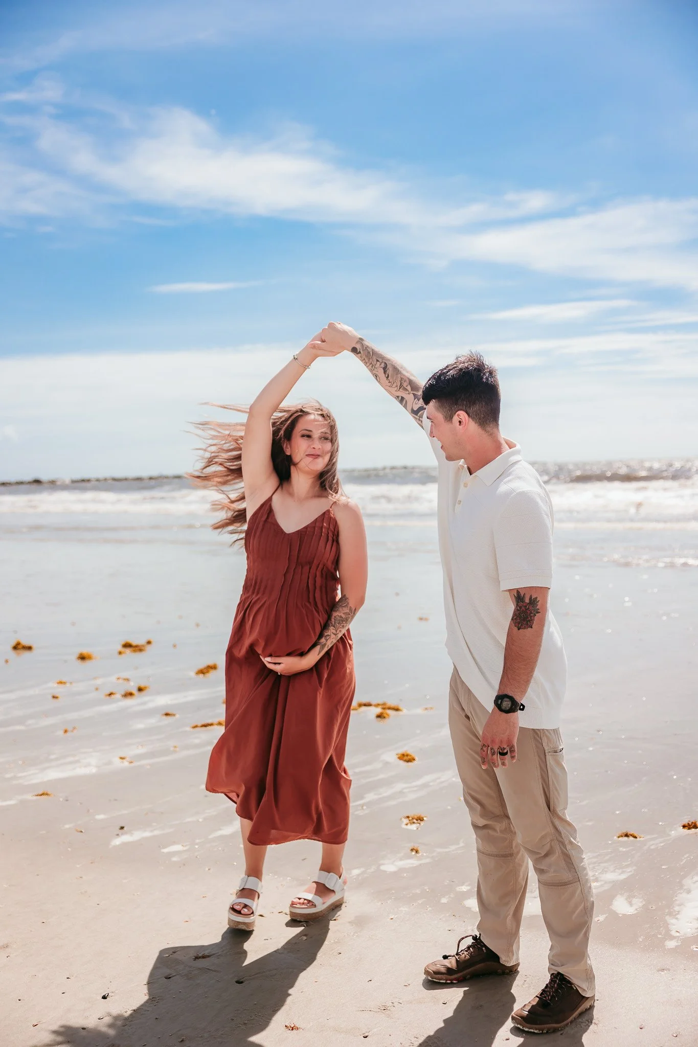 Expecting parents twirling together during a fun maternity photography session on Jacksonville Beach, Florida.