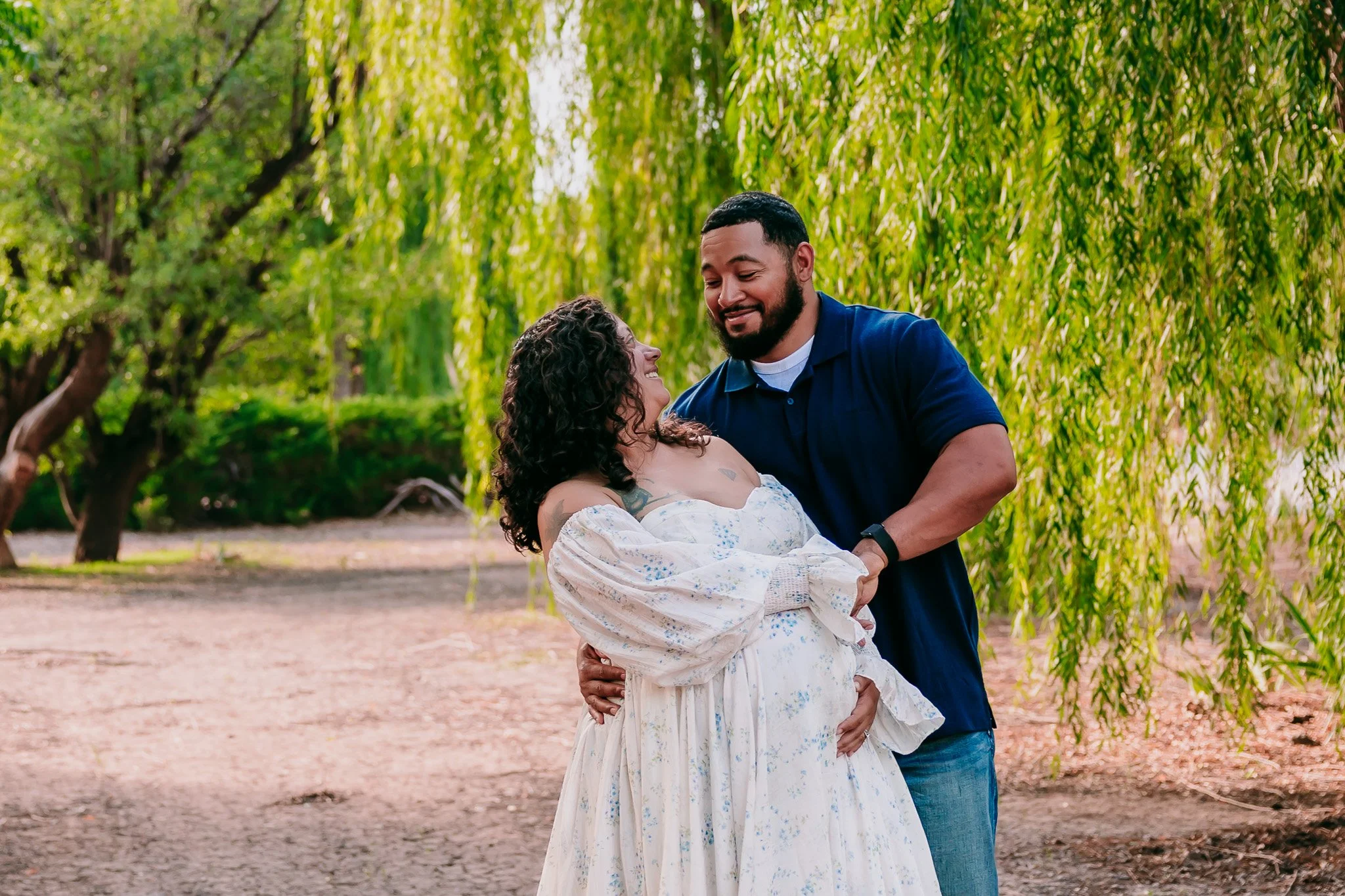 Couple laughing together while celebrating their pregnancy during a maternity photography session in Las Cruces.
