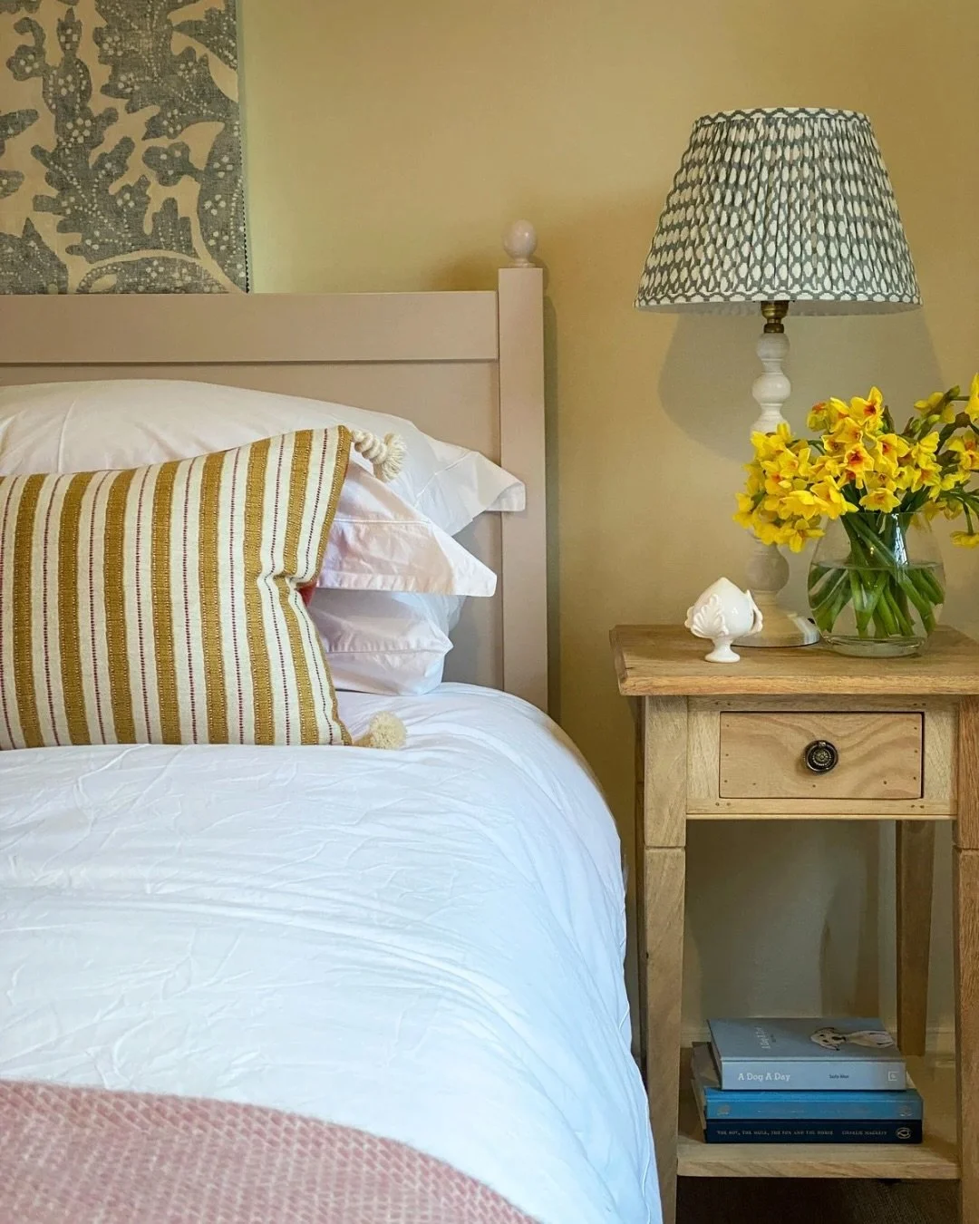 Soft layers, gentle pattern and a little spring sunshine by the bedside 🌼 A lovely guest bedroom we designed last year to feel restful, welcoming and uplifting. We adore the punch of colour from the gorgeous @village_london cushions #interiors #coun