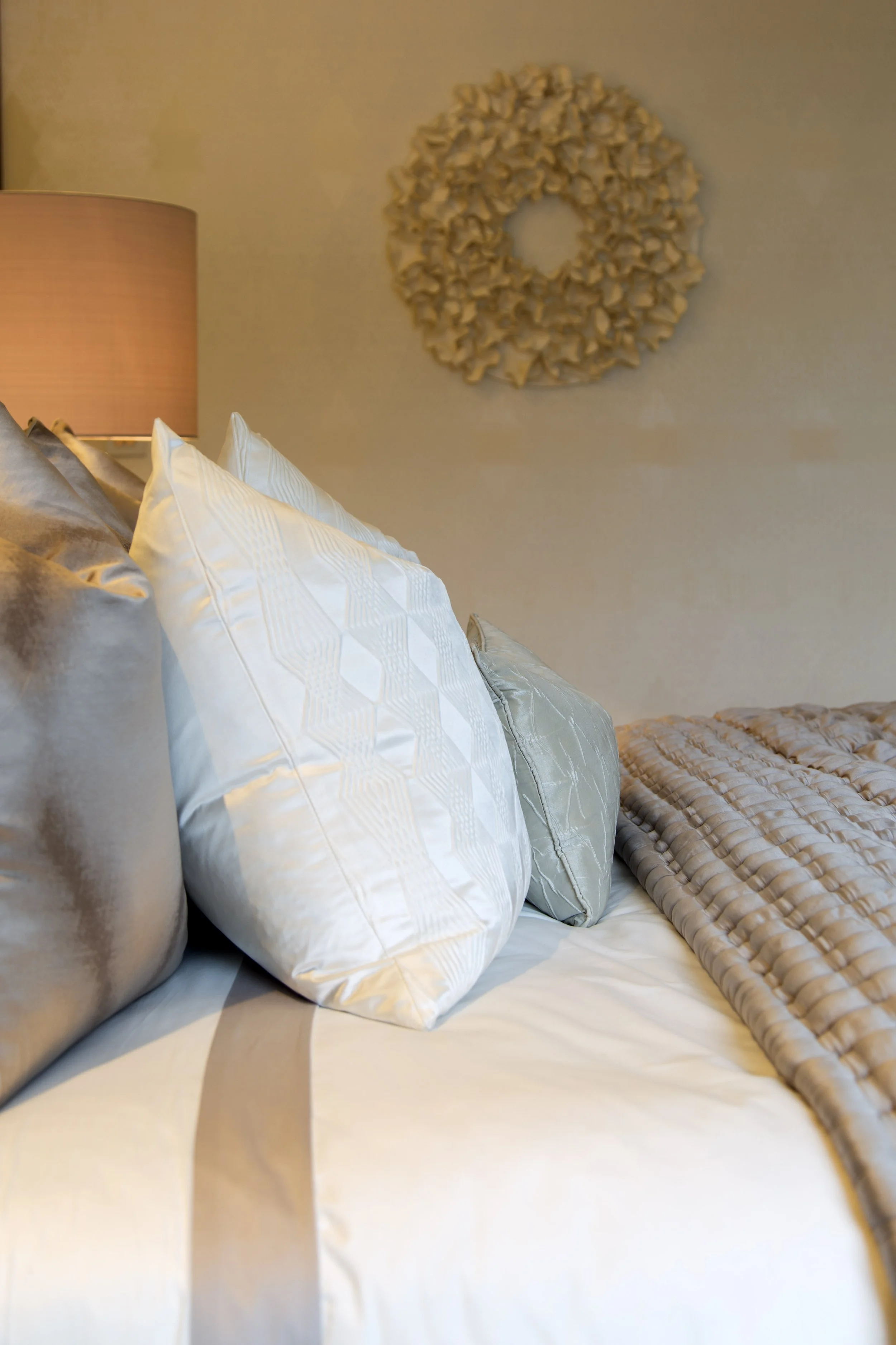 Calm master bedroom with layered bedding, soft lighting and a neutral colour palette.