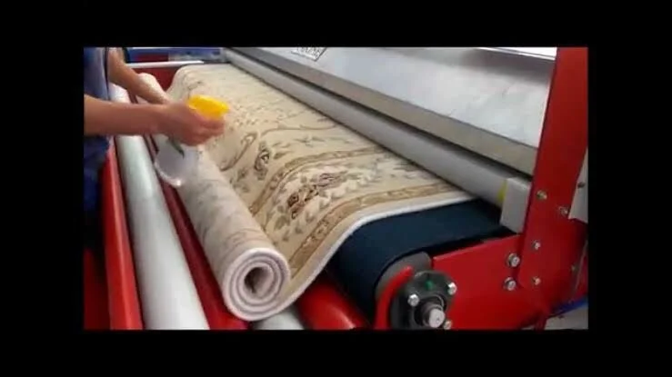 Bir makine desenli halı veya kilim basarken, yanında sprey şişesi tutan bir kişi.