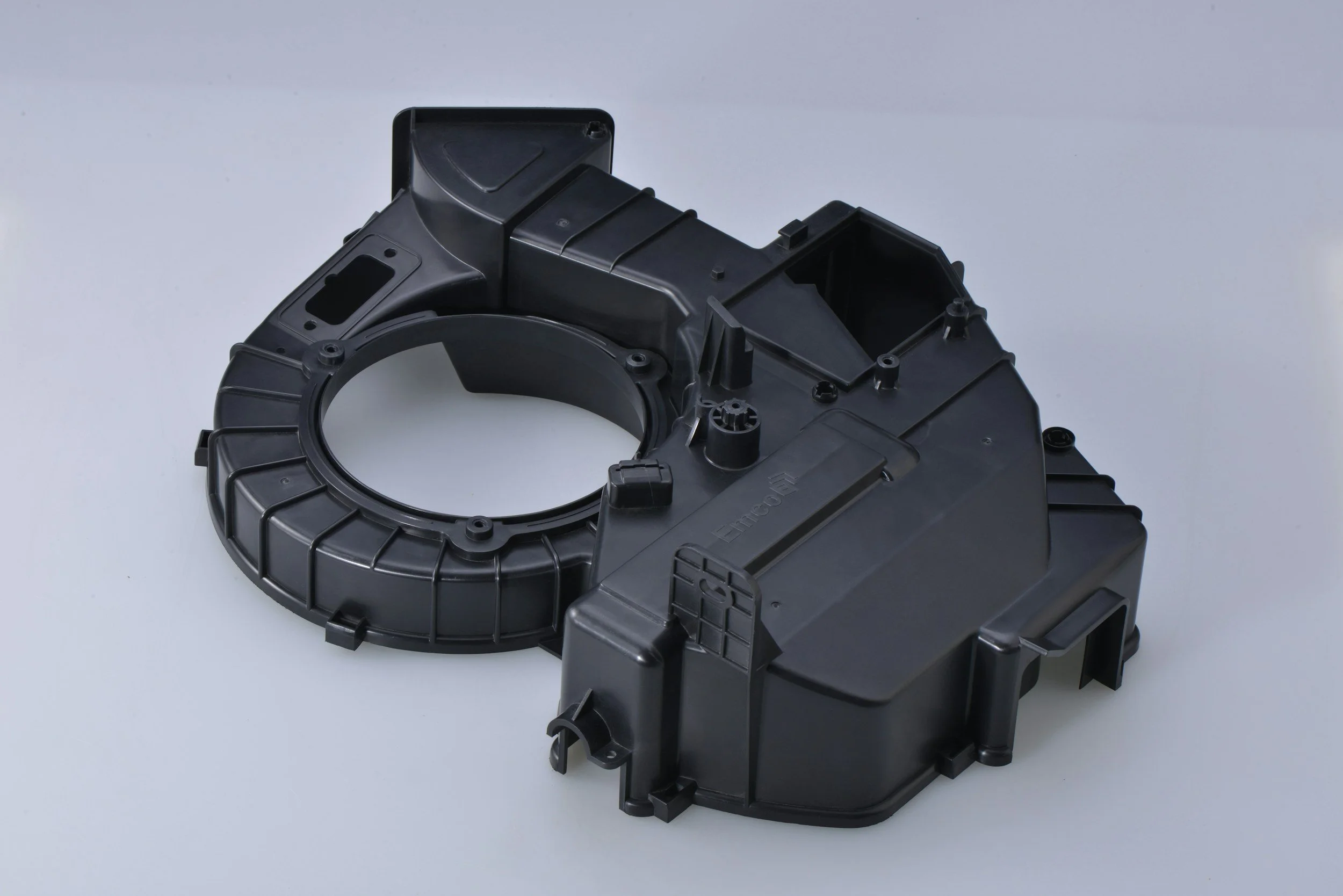 Black plastic automotive part with circular and rectangular sections on a white background.