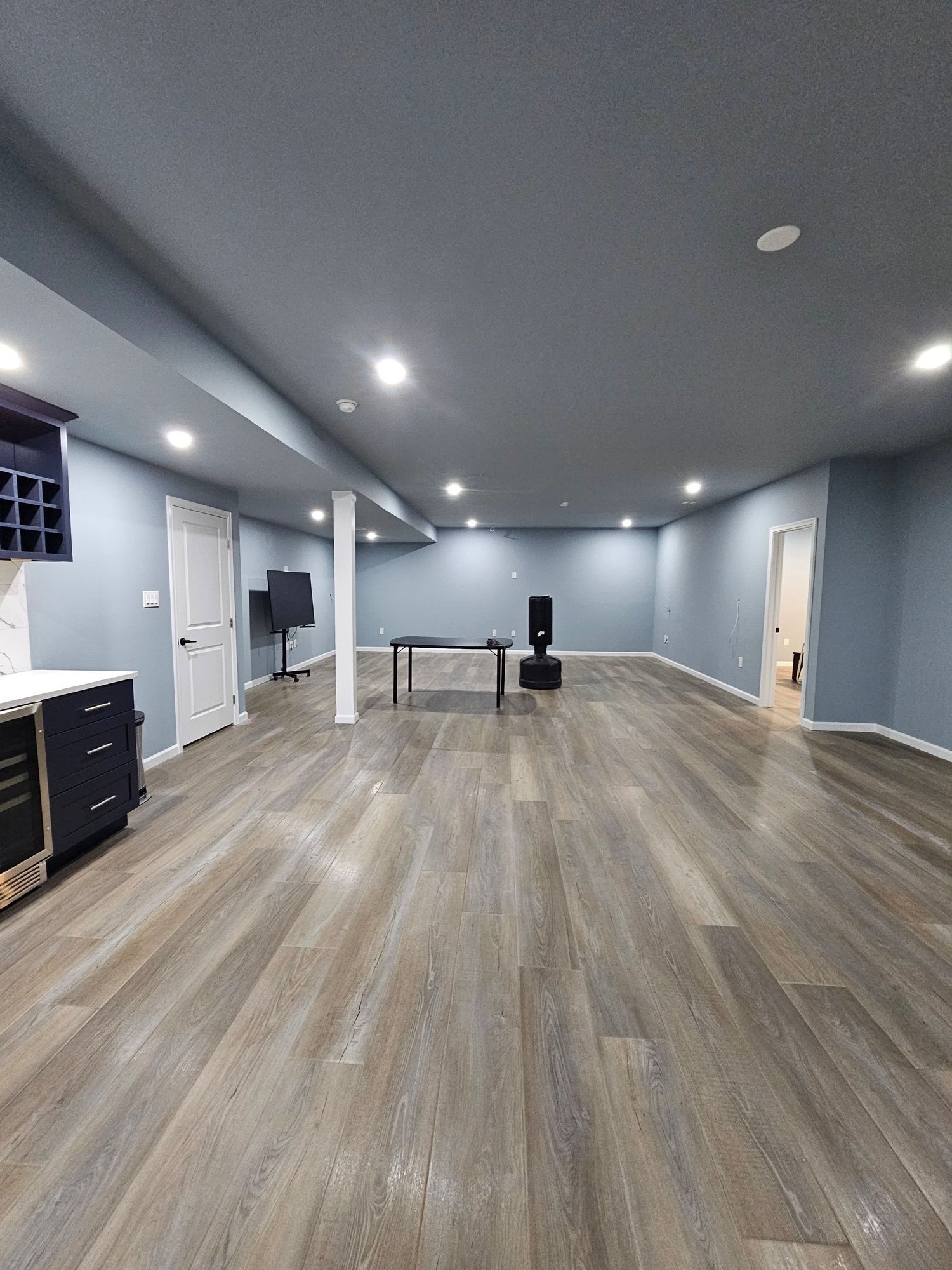 Finished basement family room with built-in shelving and recessed lighting
