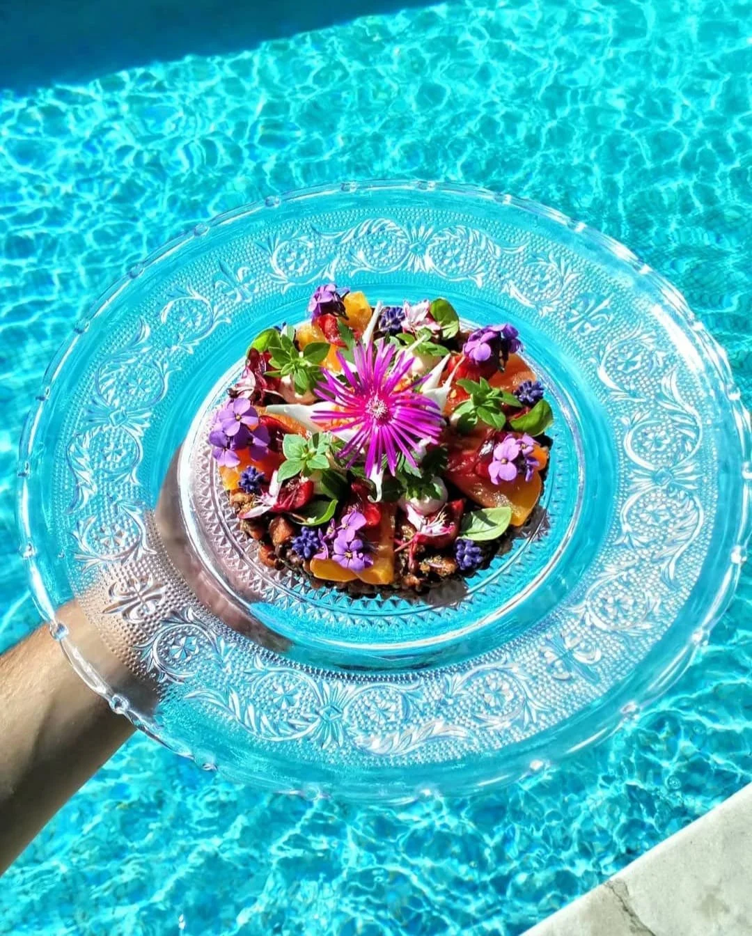 plat de nourriture décoré de fleurs, tenu au-dessus d'une piscine en plan rapproché