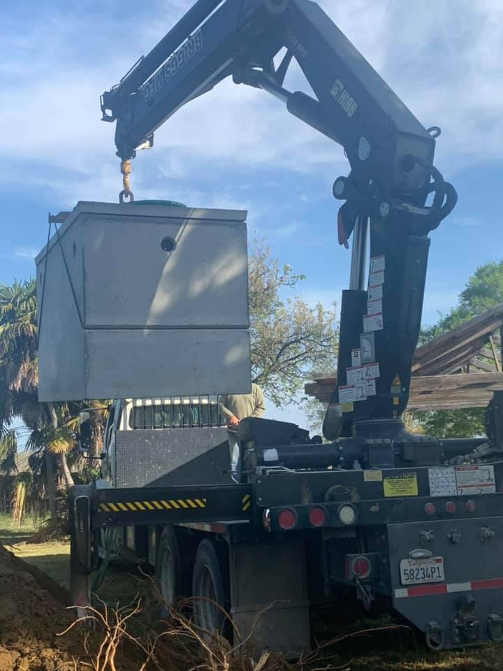 A Robert Burt Construction crane truck lifting a large metal container at a construction site outdoors.