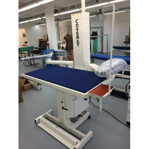 Table de physiothérapie avec support de bras et barre pour exercices de rééducation dans un centre de soins.