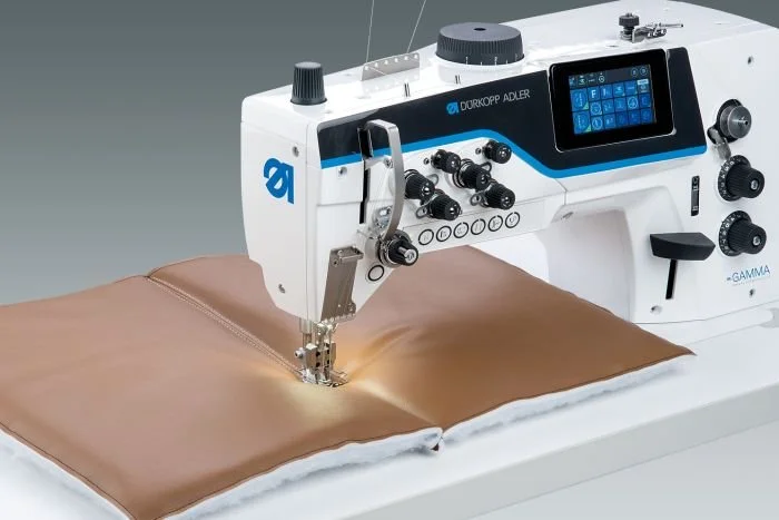 Machine à coudre industrielle cousant du cuir marron.