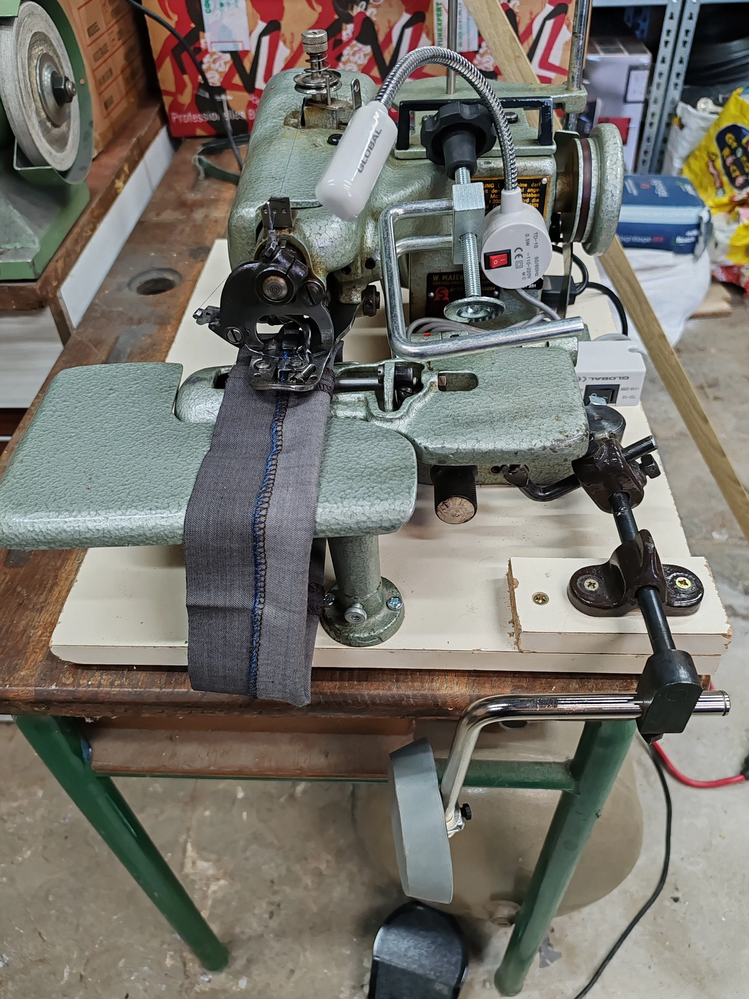 Une machine à coudre industrielle sur une table en bois.