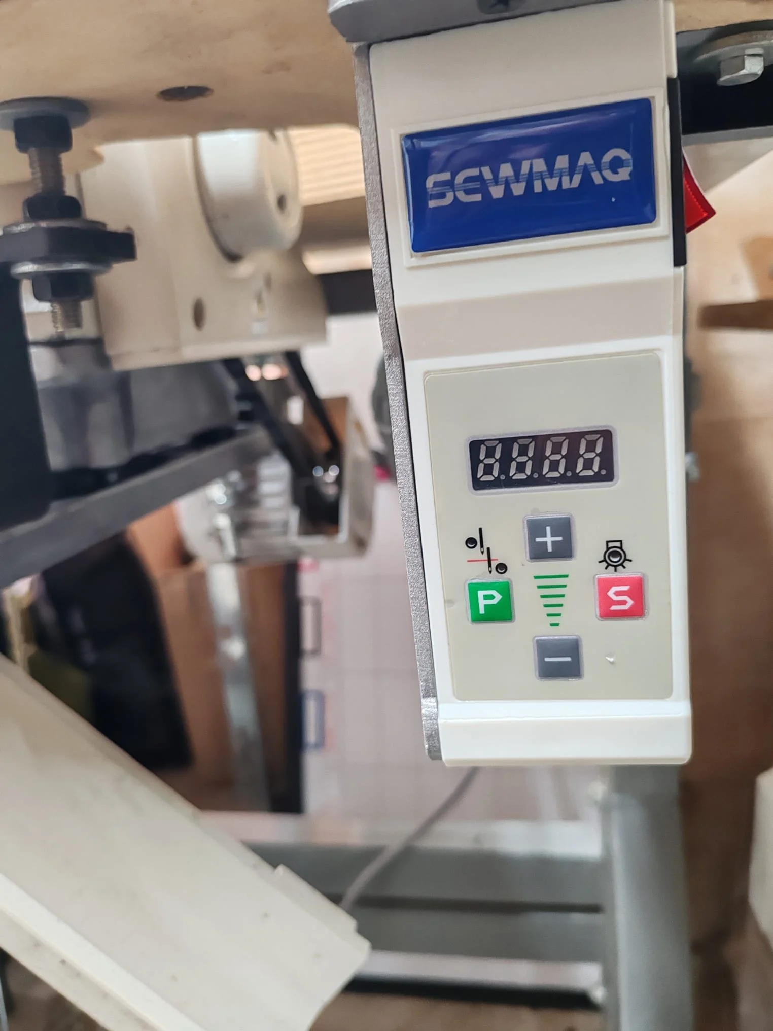 Un périphérique de contrôle numérique monté sur une machine, avec des boutons pour régler la vitesse ou l'intensité, une petite étendue d'affichage numérique et des indicateurs lumineux verts et rouges.