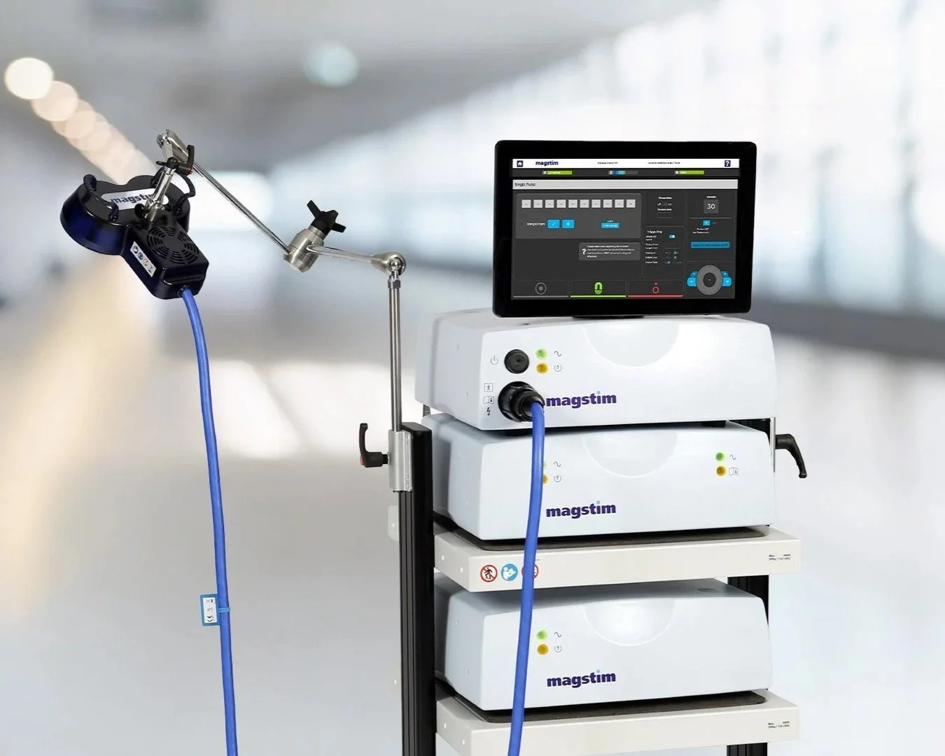 Medical devices with a monitor displaying software interface on a tray with a blue cable attached.