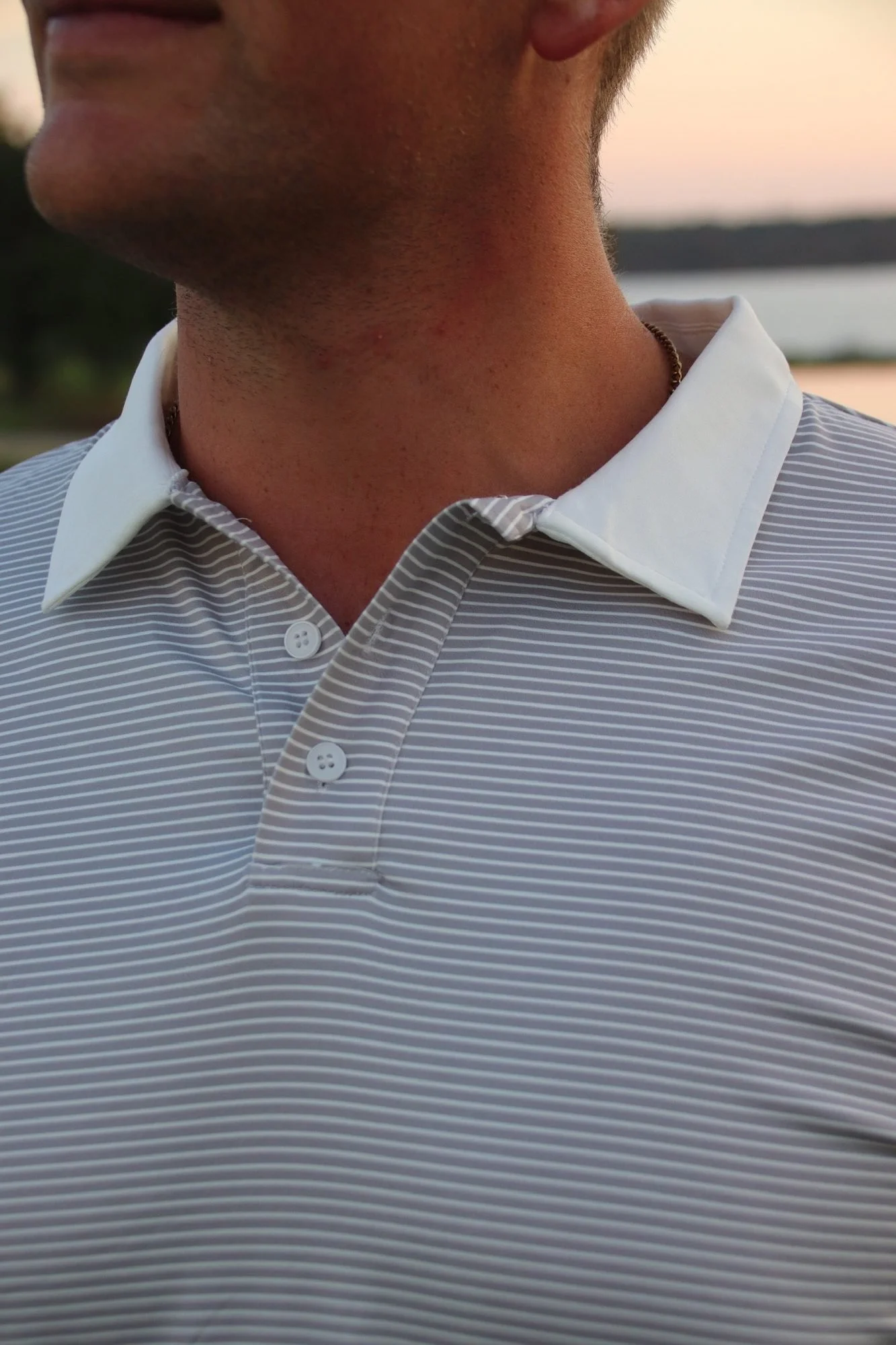 Close-up of the white collar and button placket on The Striped Classic polo in gray